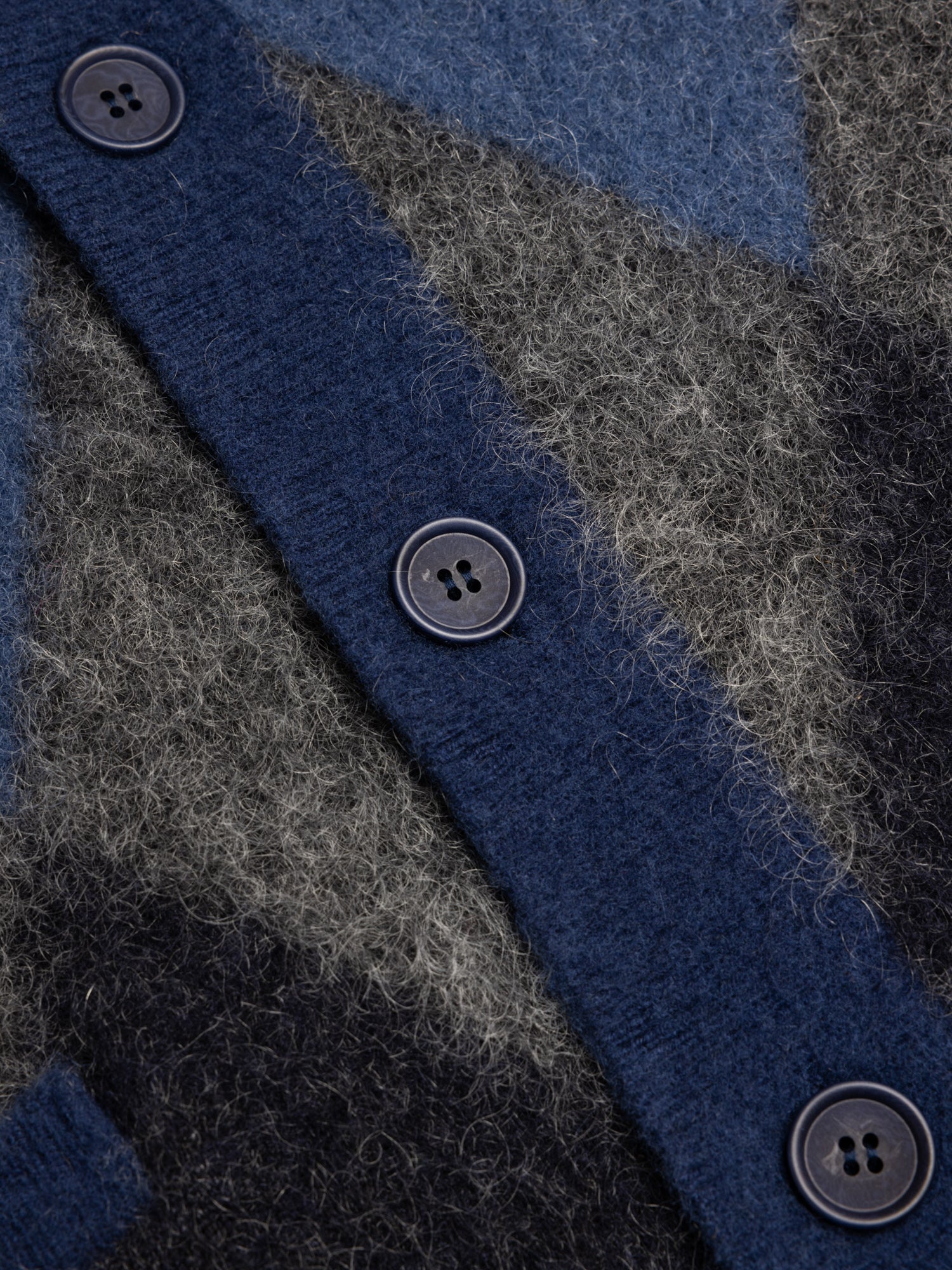 Close-up of a textured wool fabric with buttons on a blue and gray patterned background
