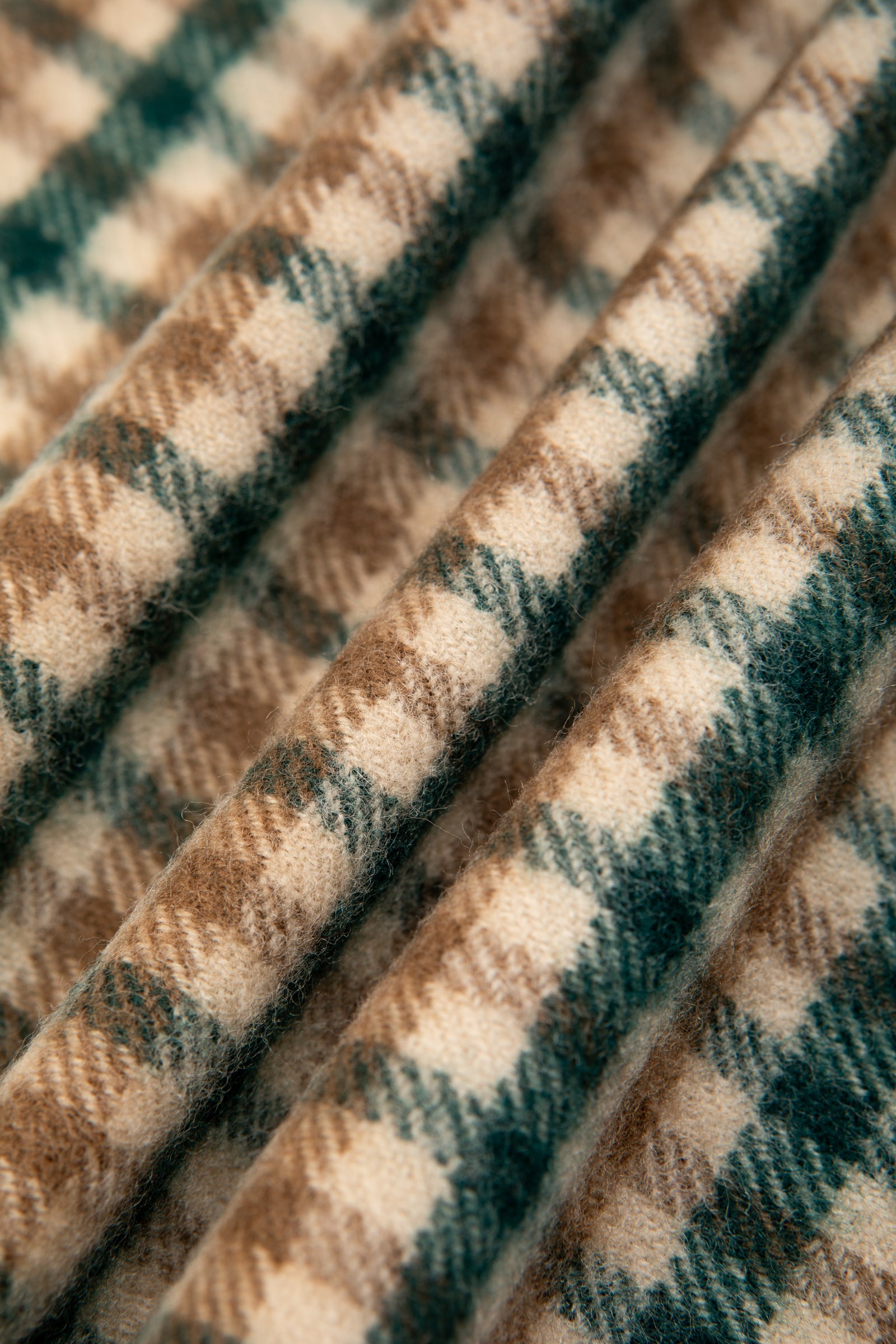 A close-up of a lambswool fabric in a green and brown check