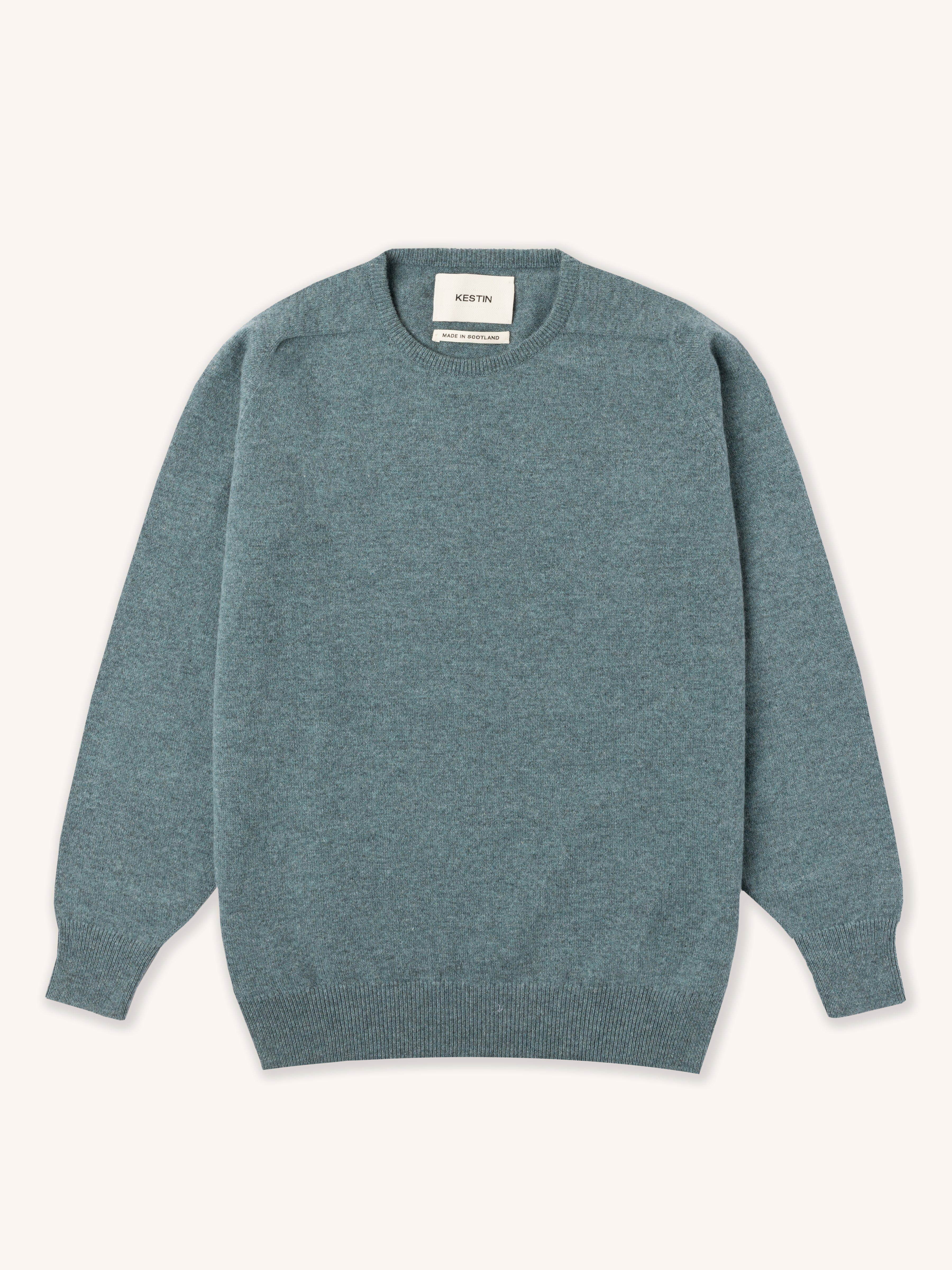 Teal green lambswool sweater on a white background
