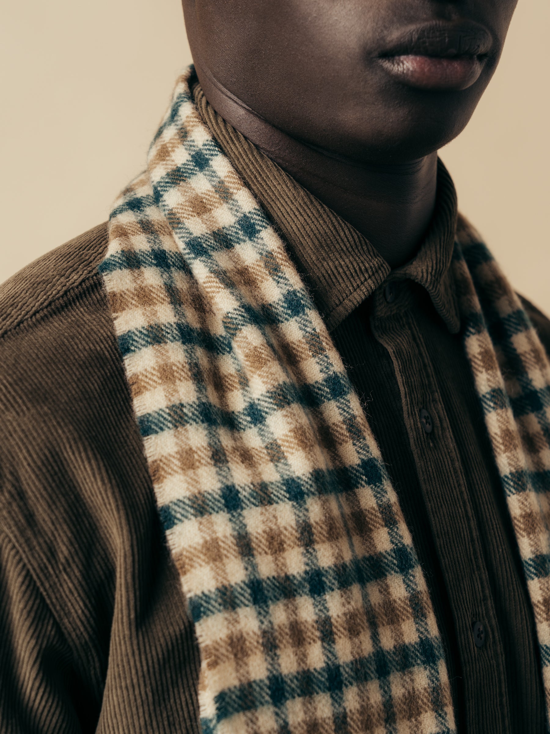 A brown and green checked lambswool scarf worn with a corduroy olive shirt