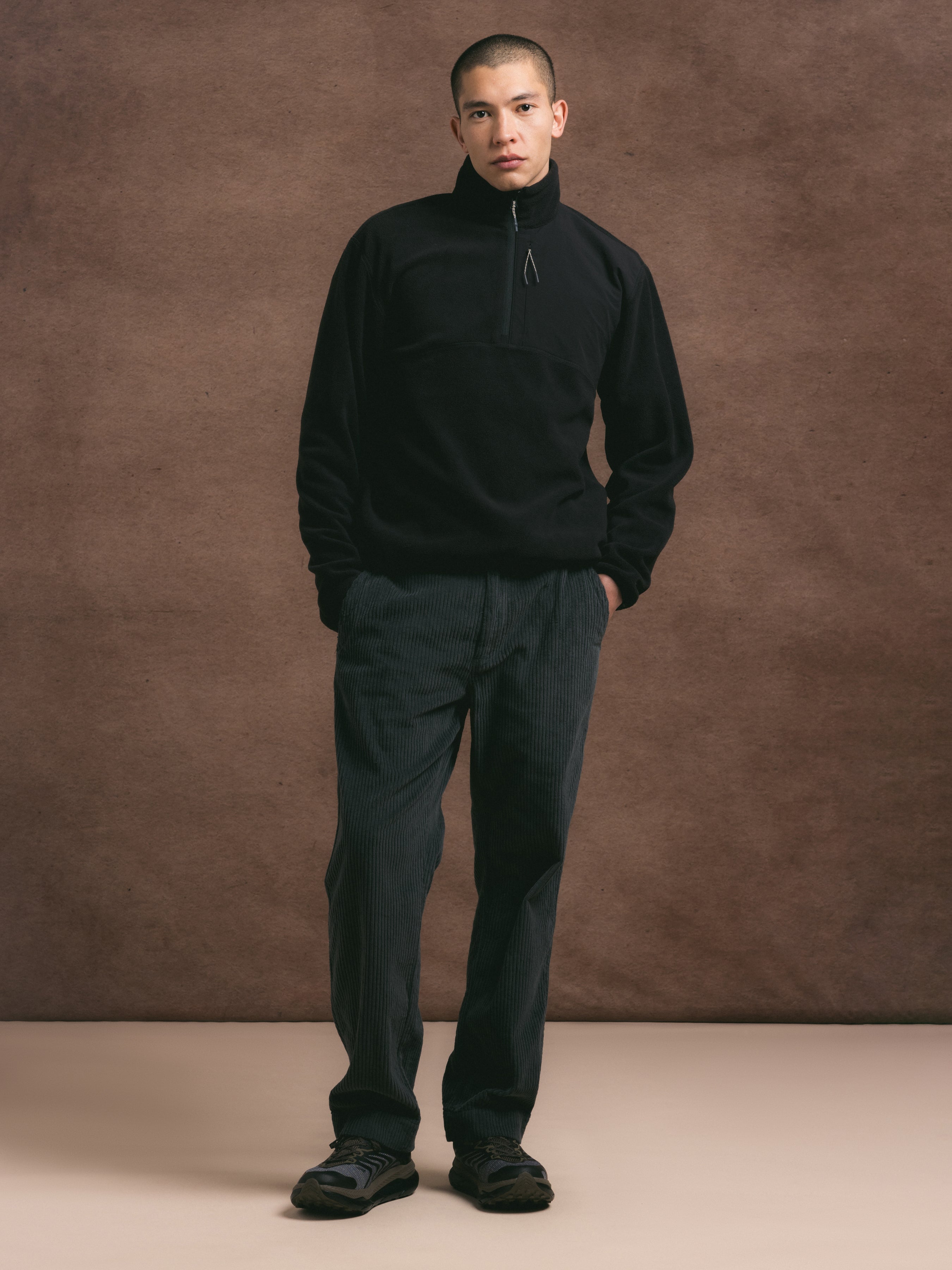 Man wearing a black outfit against a brown background