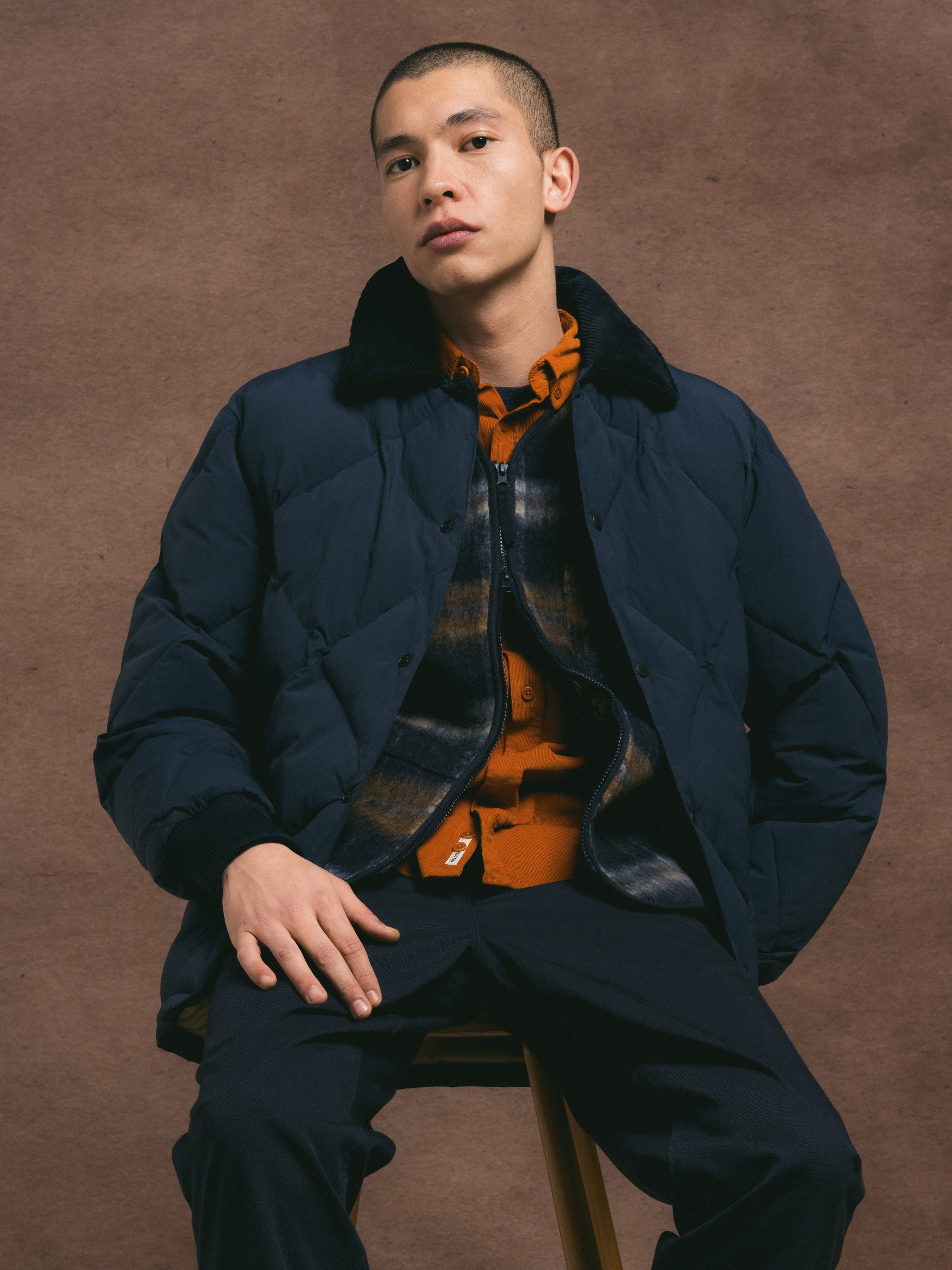 Man wearing a dark blue coat with a brown background