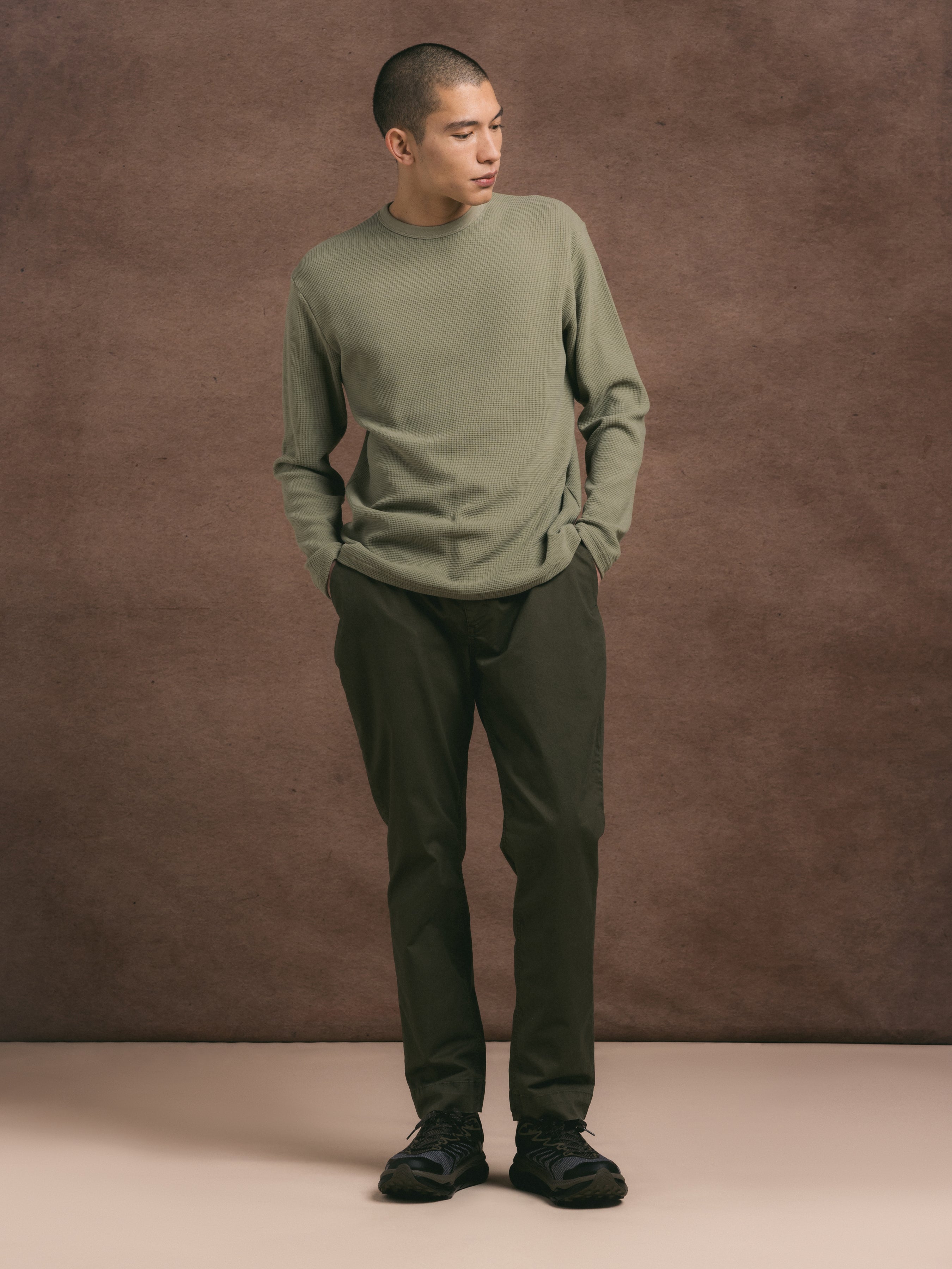 A model wearing a cotton waffle fabric long sleeve tee against a textured brown background