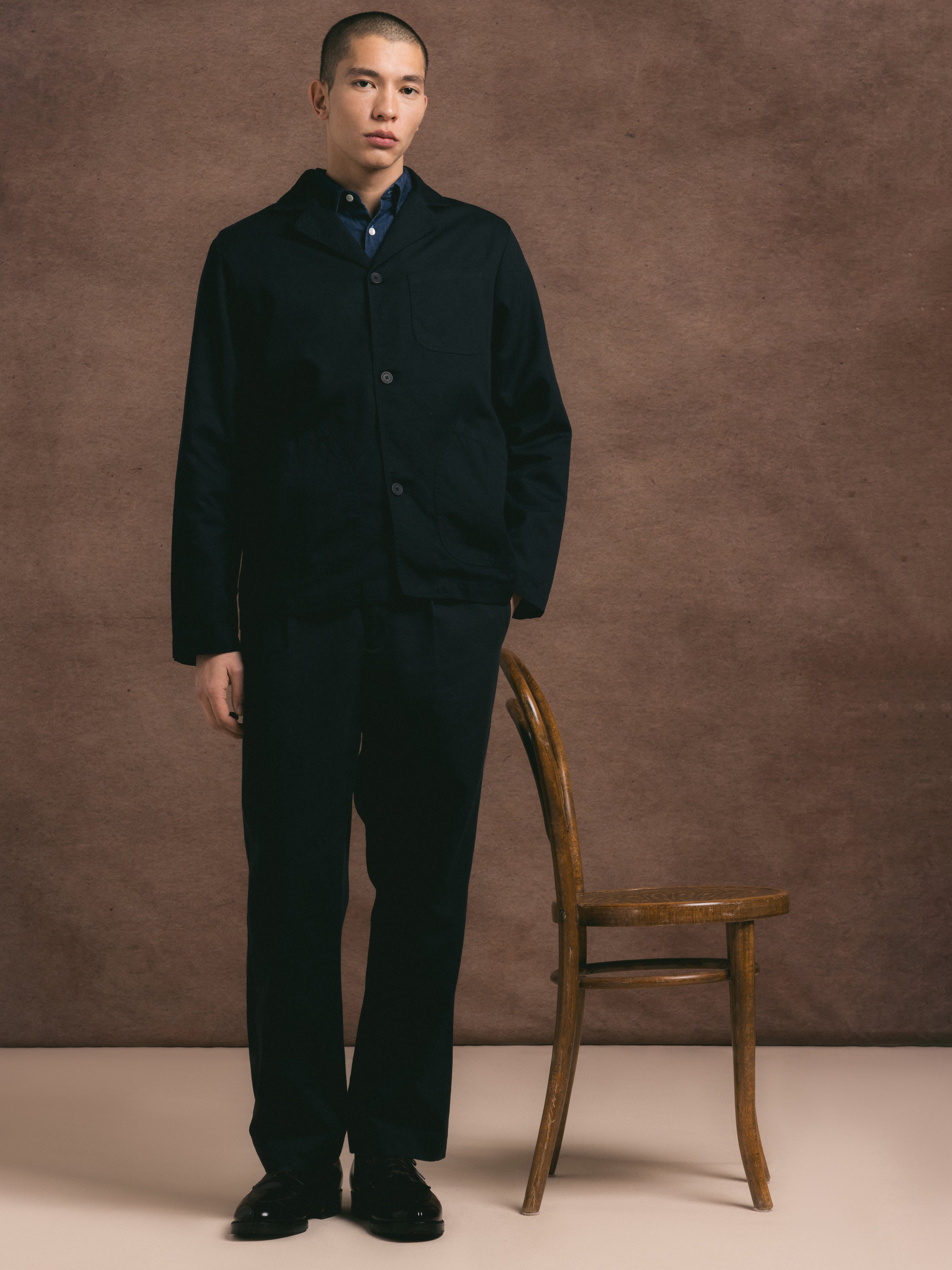 A model wearing a regular fitting two piece suit in dark navy cotton twill paired with a navy shirt