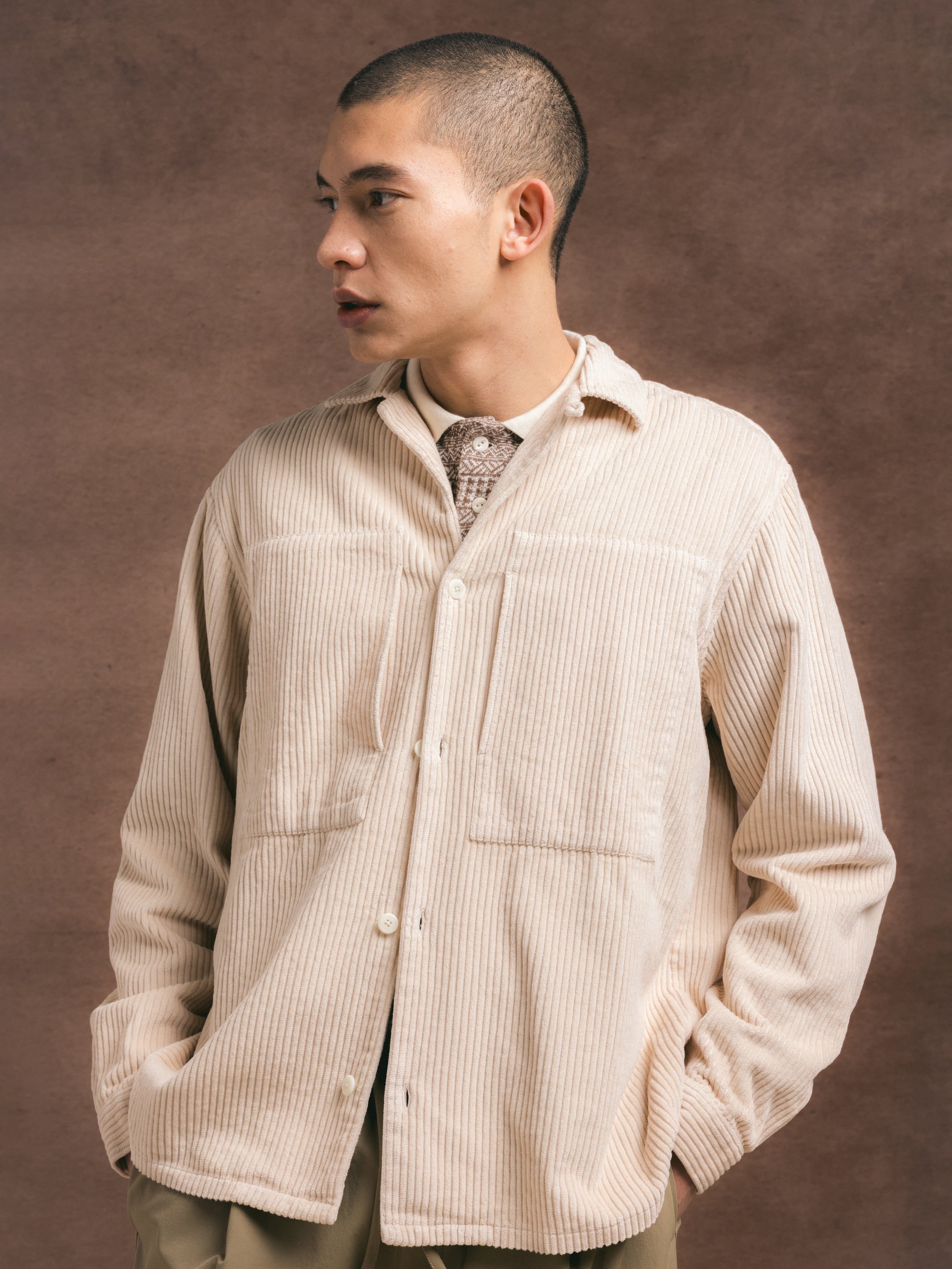 A man wearing a white corduroy shirt over a textured polo shirt