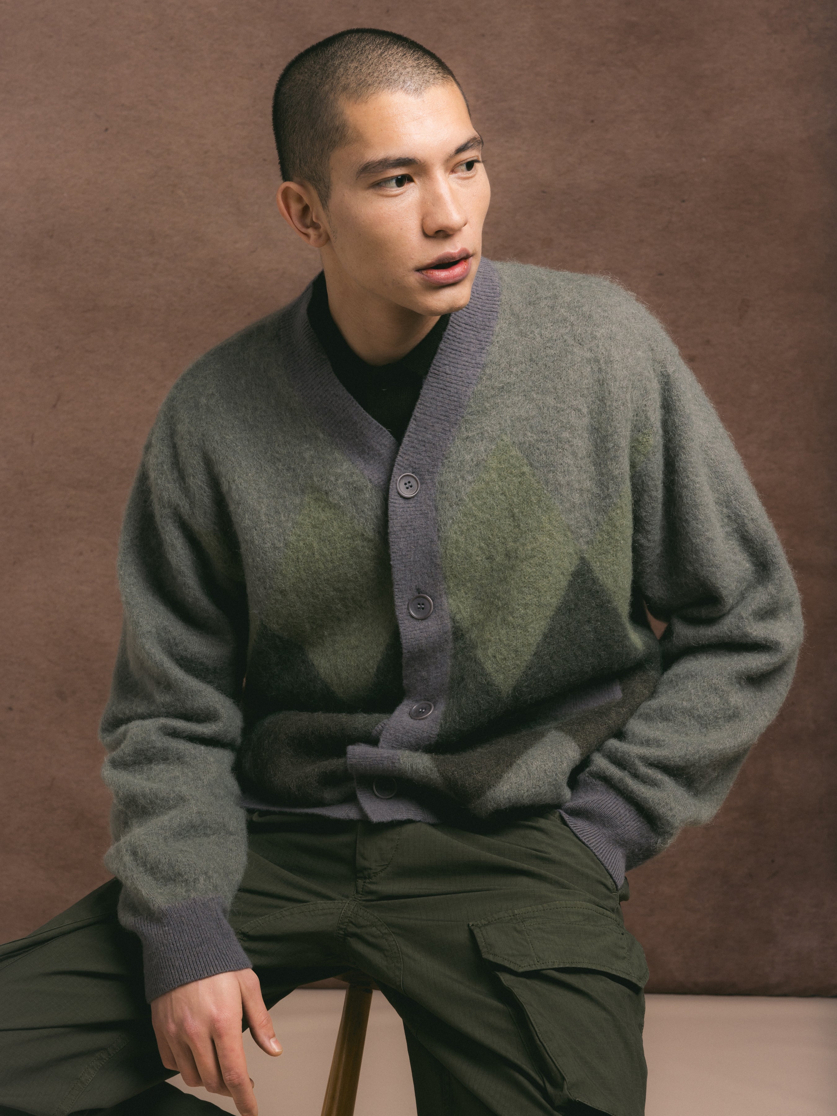 Man wearing a green patterned sweater against a brown background