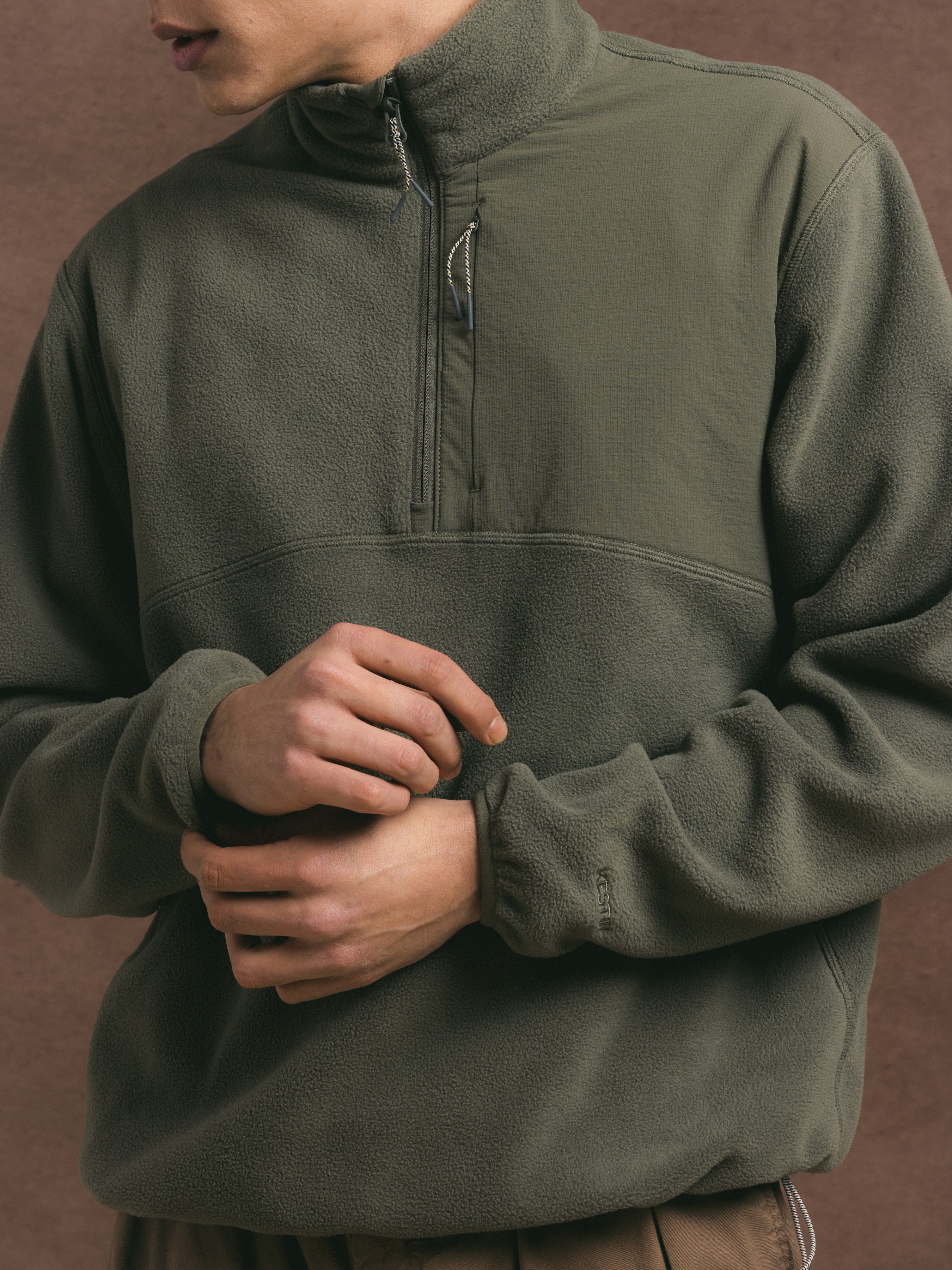 Person wearing a green fleece pullover against a brown background