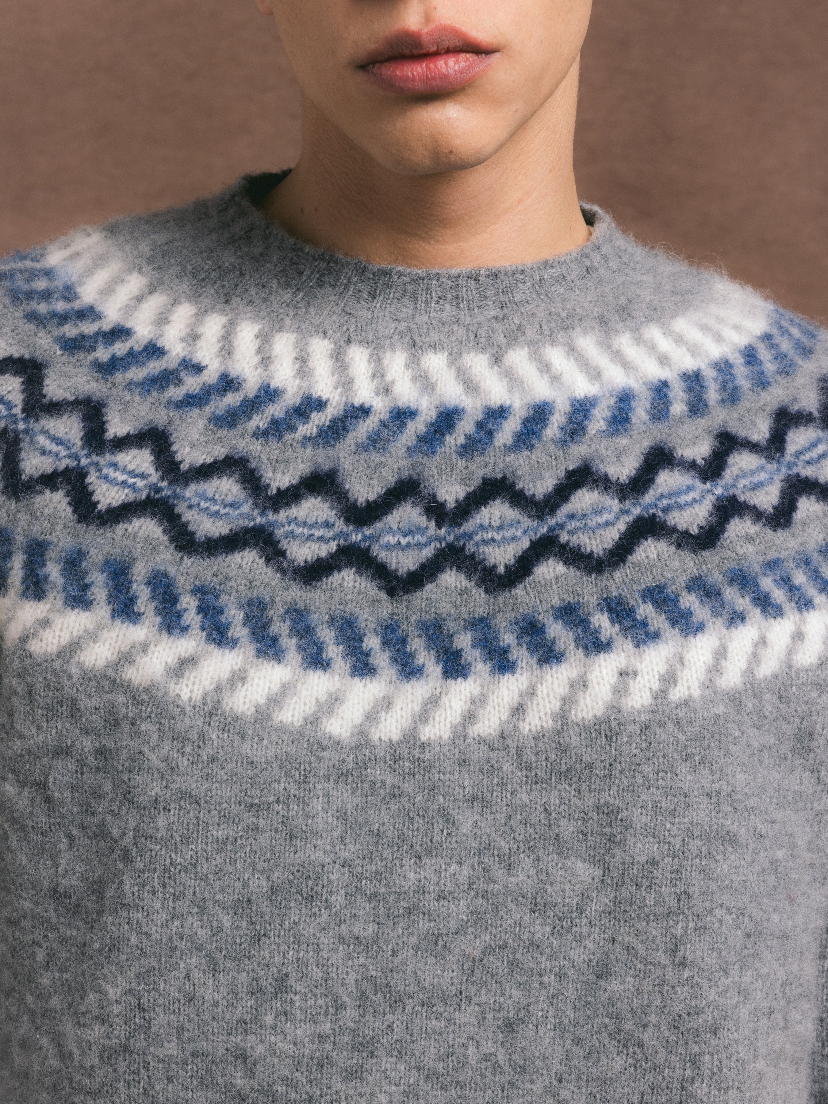 A detailed view of a grey knitted crew featuring a traditional scottish fairisle yoke design, soft and warm pure new wool detailing.