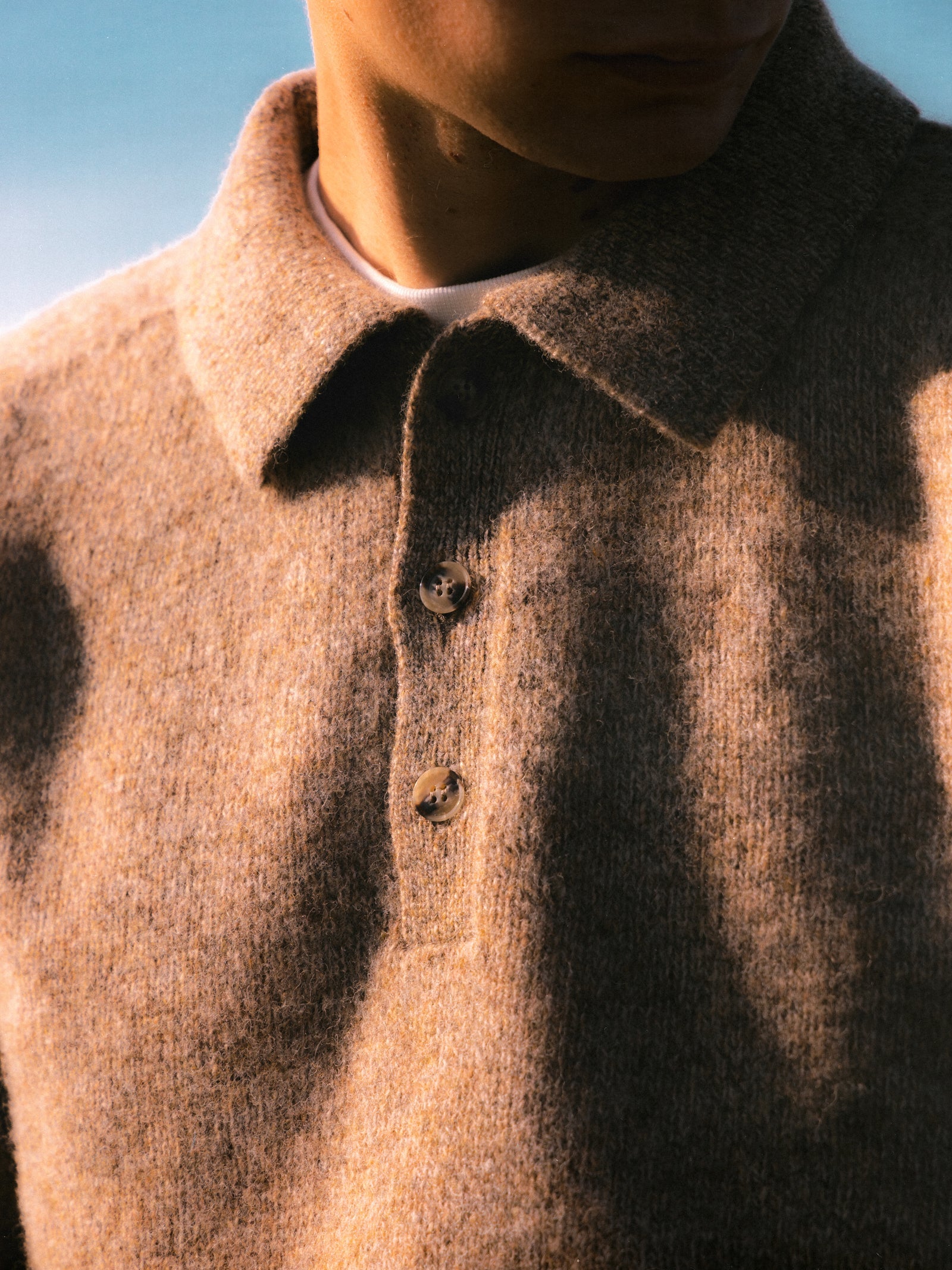The buttoned neck on a knitted polo sweater, made in Scotland.