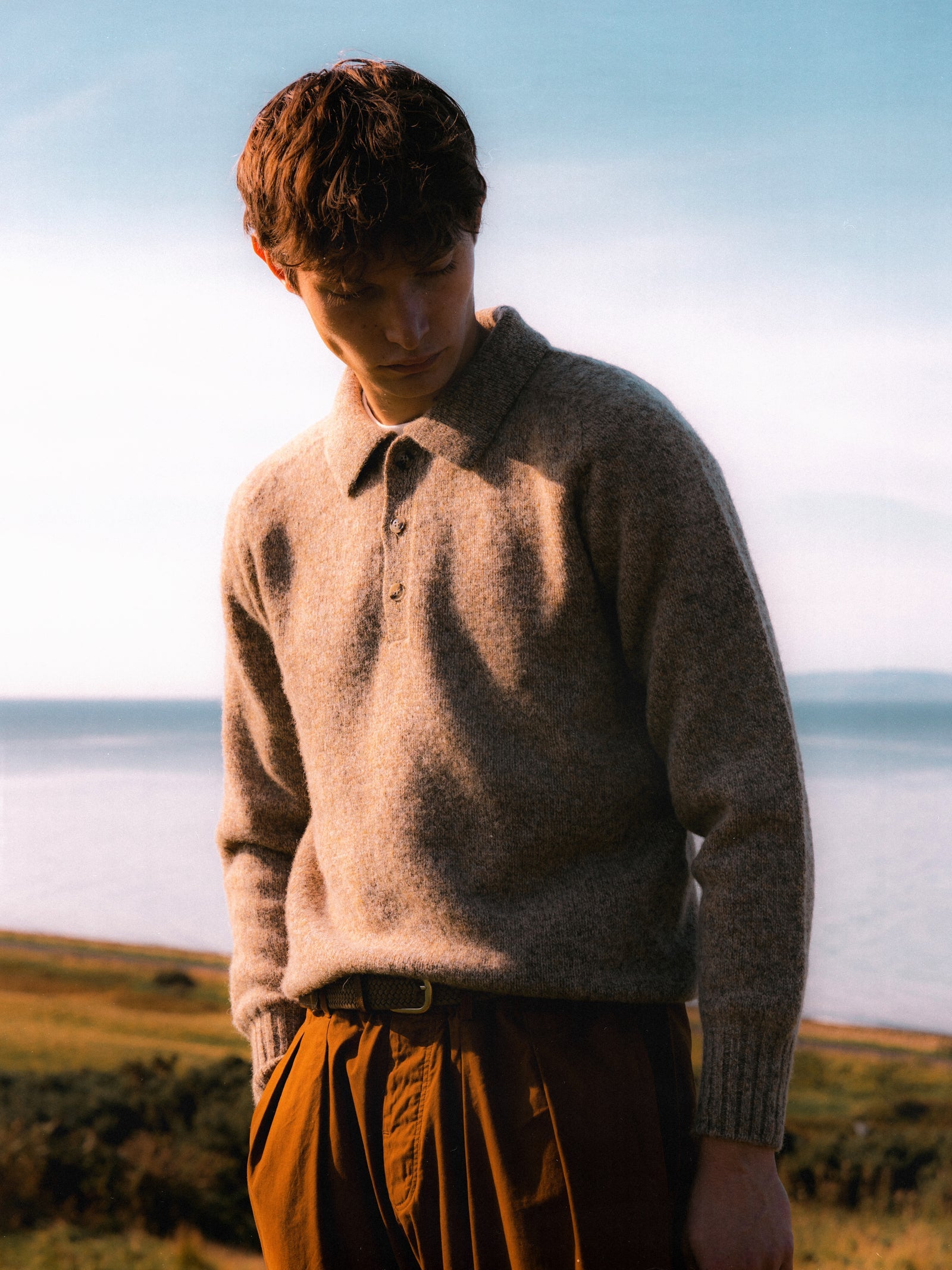 A model wearing a knitted wool polo sweater in beige.