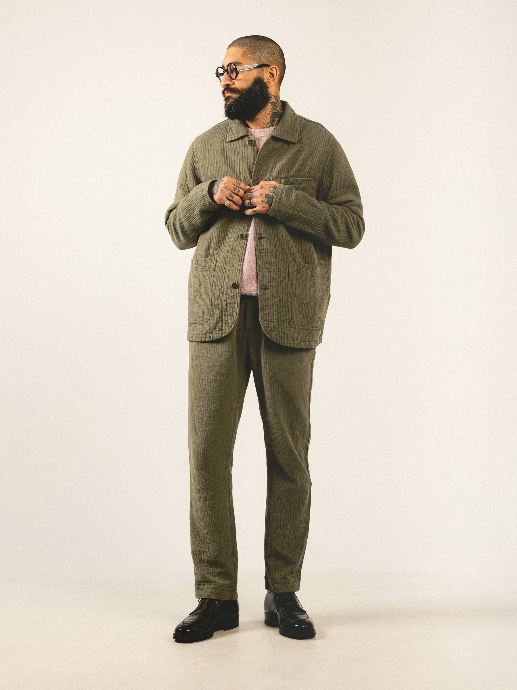 A model wearing a green suit, consisting of a chore coat and regular fit trousers.