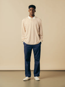 A model wearing denim jeans and a striped polo shirt from menswear brand KESTIN.