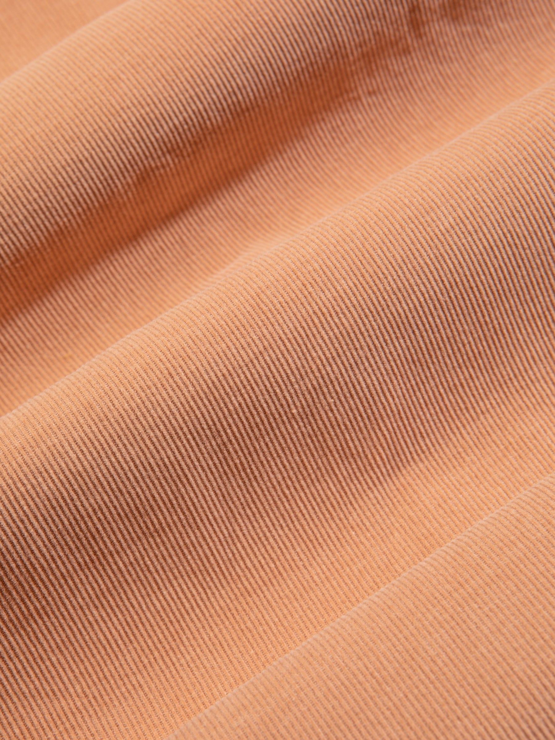 An organic cotton needlecord fabric in a terracotta pink colour.