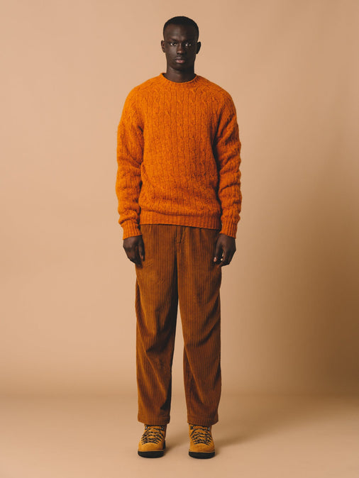 A man wearing an orange knitted sweater, made from brushed shetland wool.
