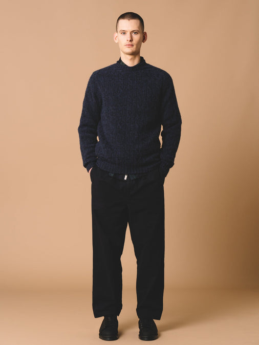 A man wearing trousers and a knitted sweatshirt by Scottish menswear brand KESTIN.
