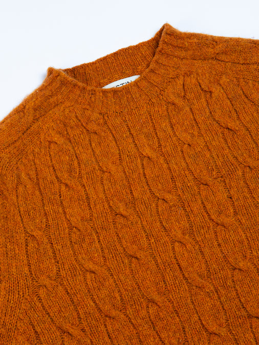 A close-up of the Galloway Cable Knit Sweater in Tangerine Orange, on a white background.
