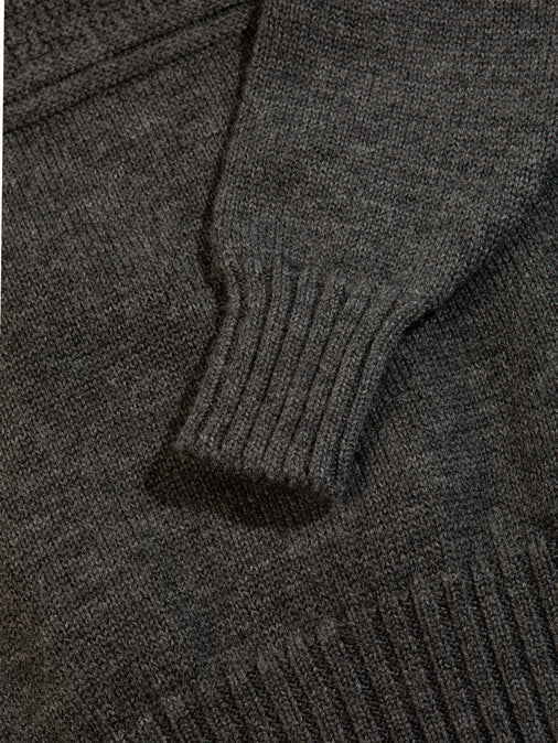 The ribbed hem and cuff from a men's knitted sweater in charcoal grey.