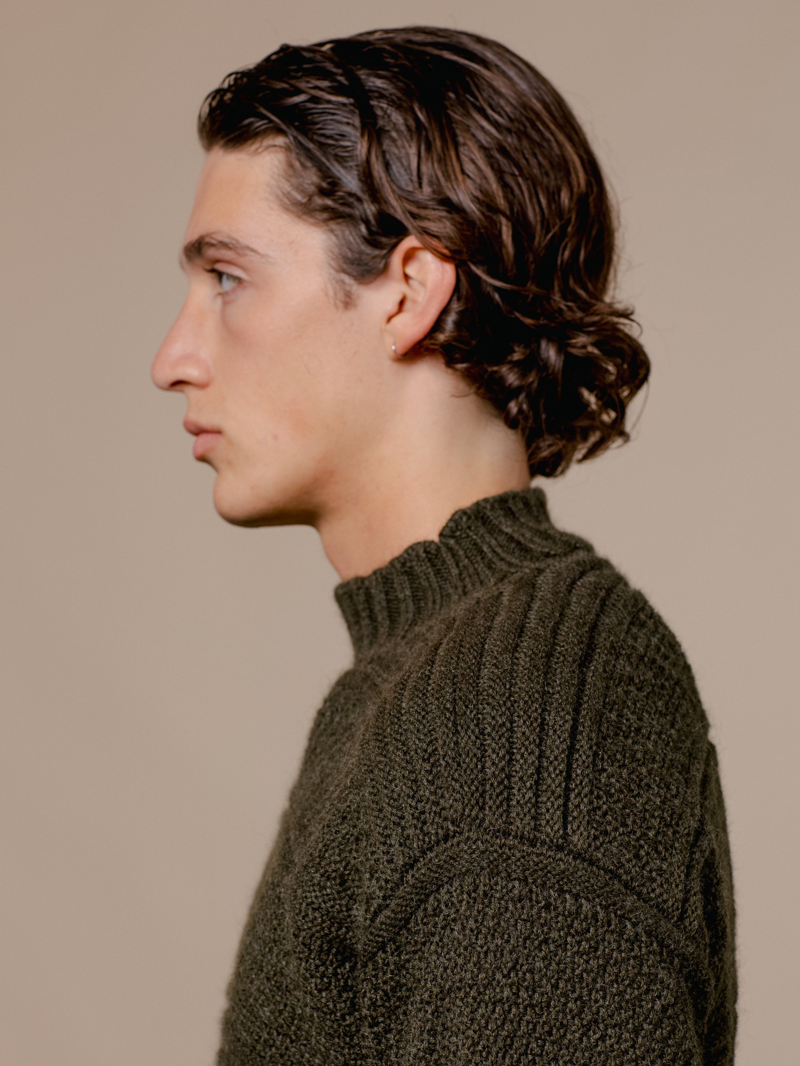 A man wearing a green knitted sweater by KESTIN, made in Scotland.