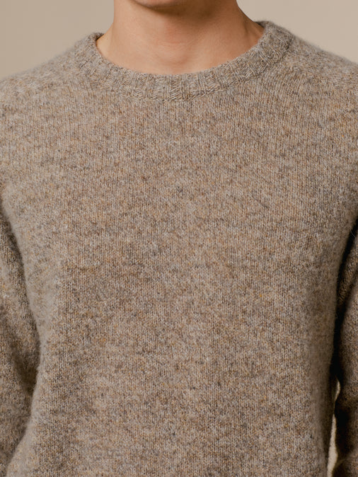 A man wearing a crew neck sweater by KESTIN, made from Shetland wool.