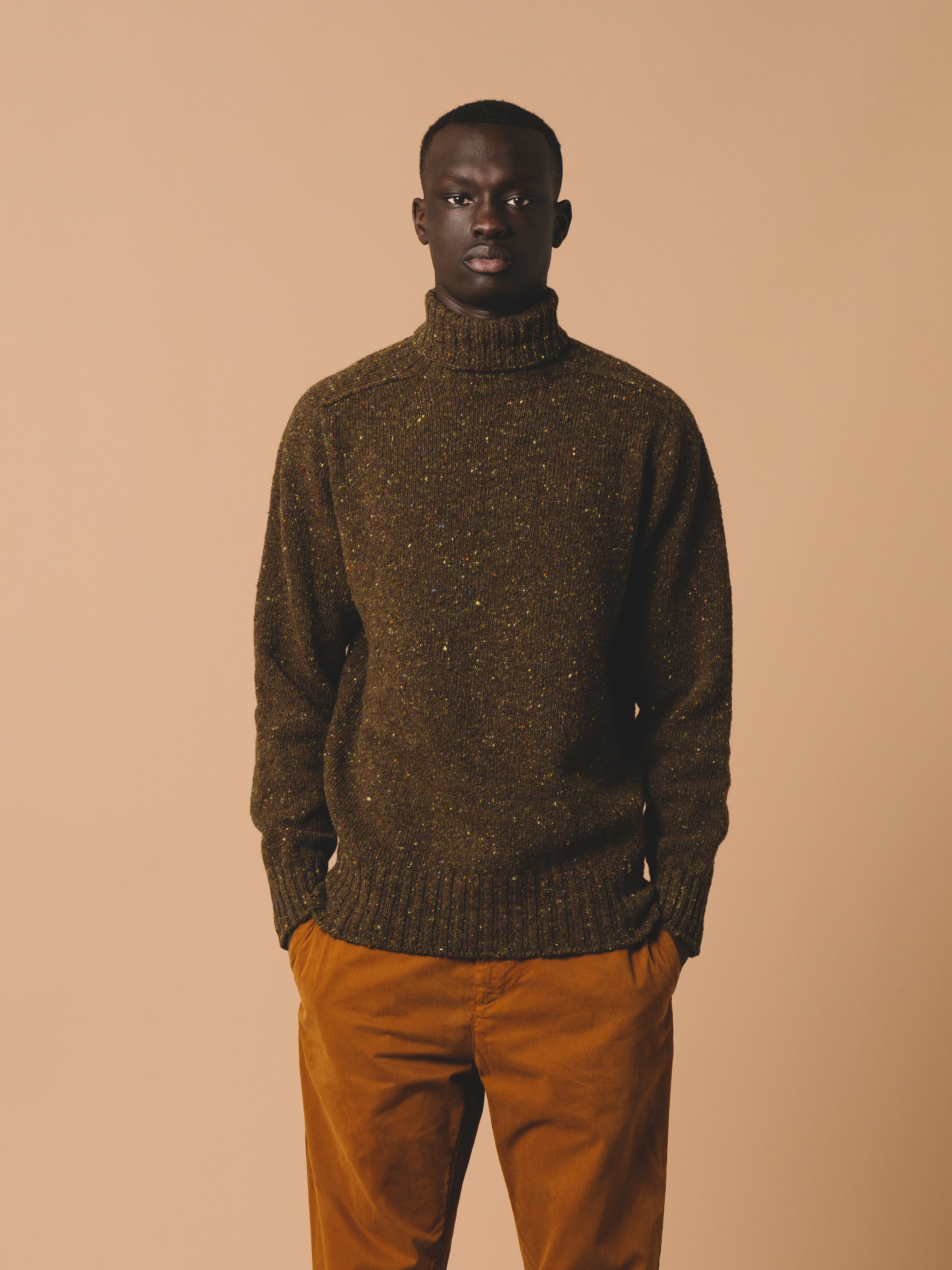 A man wearing a knitted Donegal wool sweater with a roll neck.