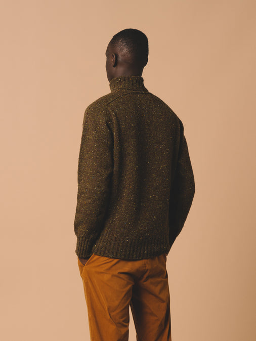 A model showing the back of the KESTIN Donegal Roll Neck Sweater in Olive Green.