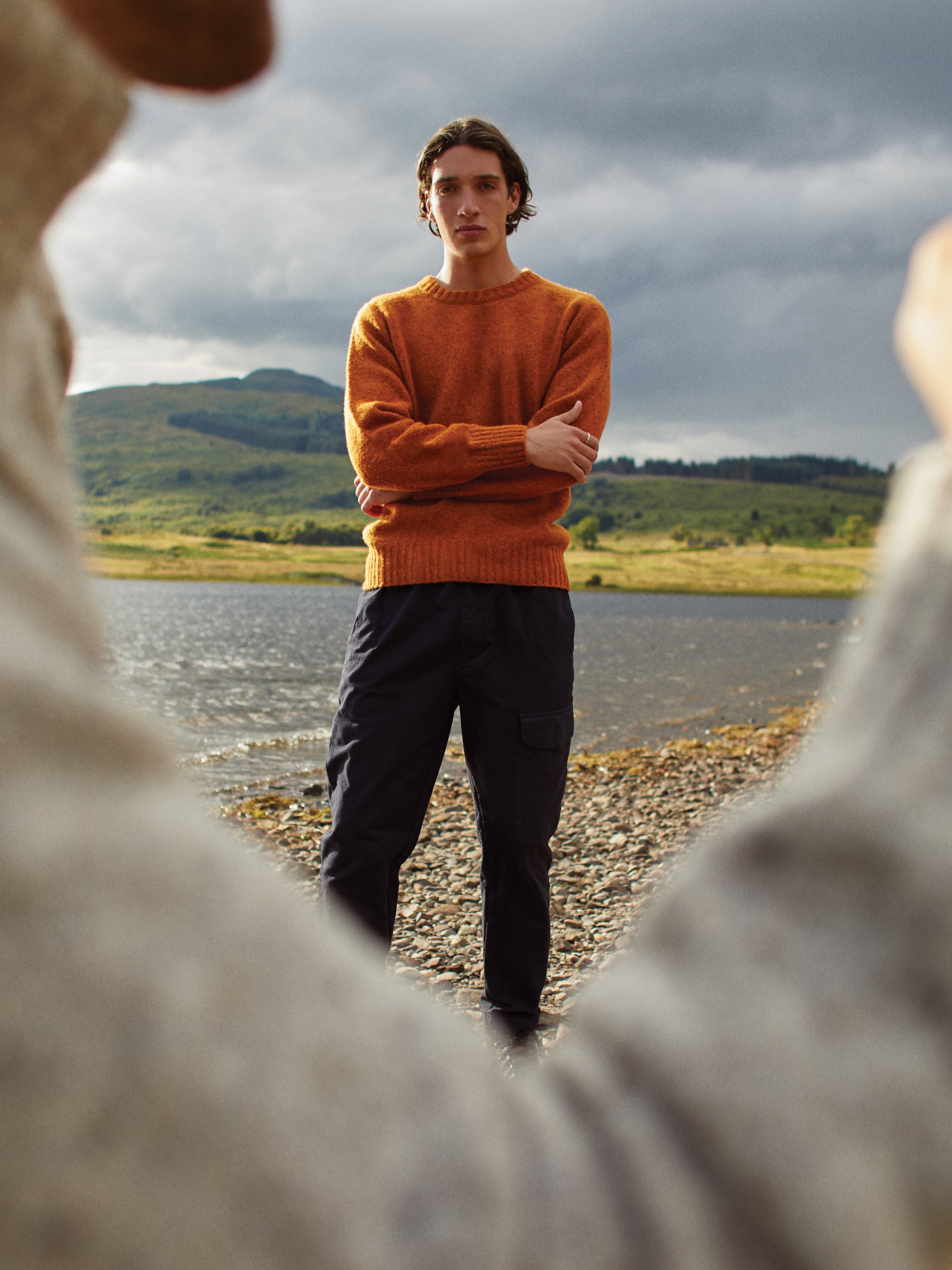 A model wearing an orange knitted sweater whilst exploring the Isle of Skye.