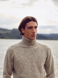 A man wearing a knitted roll neck sweater whilst exploring the Isle Of Skye.