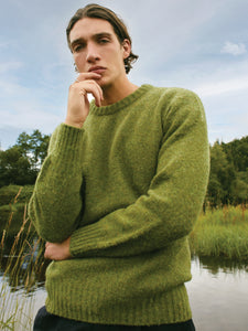 A model wearing a Shetland wool sweater in green, whilst exploring the Isle of Skye.