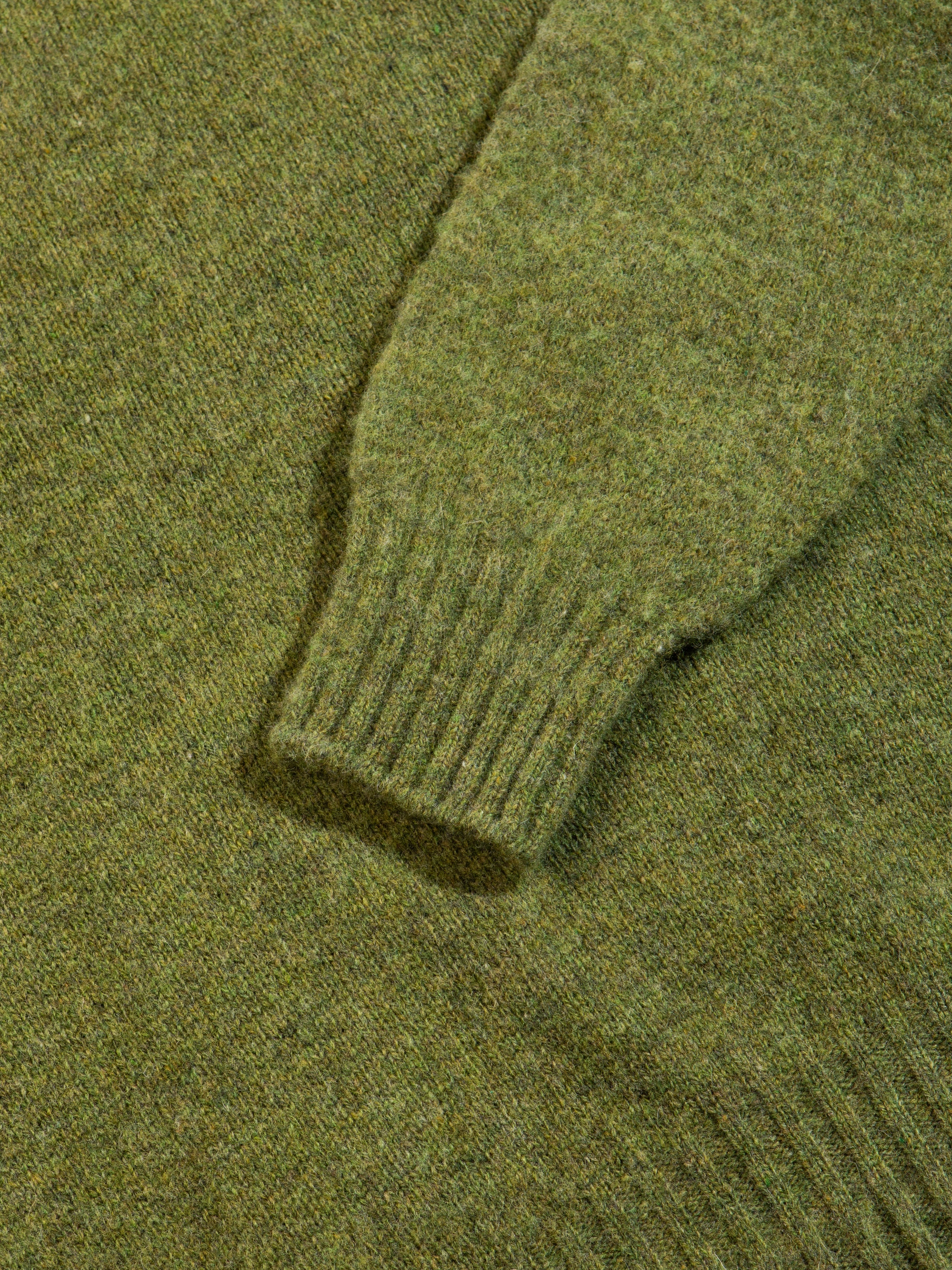 A ribbed cuff and hem on a Shetland wool sweater in green.