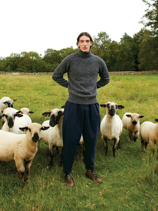 A man wearing a knitted roll neck sweater, made in Scotland from Donegal wool.