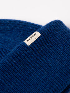 A woven logo tag sewn to the cuff of the KESTIN Braemar Beanie in cobalt blue.