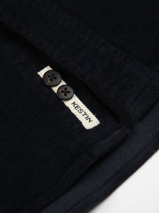 A close-up of the woven logo patch and spare buttons from a KESTIN Shirt.