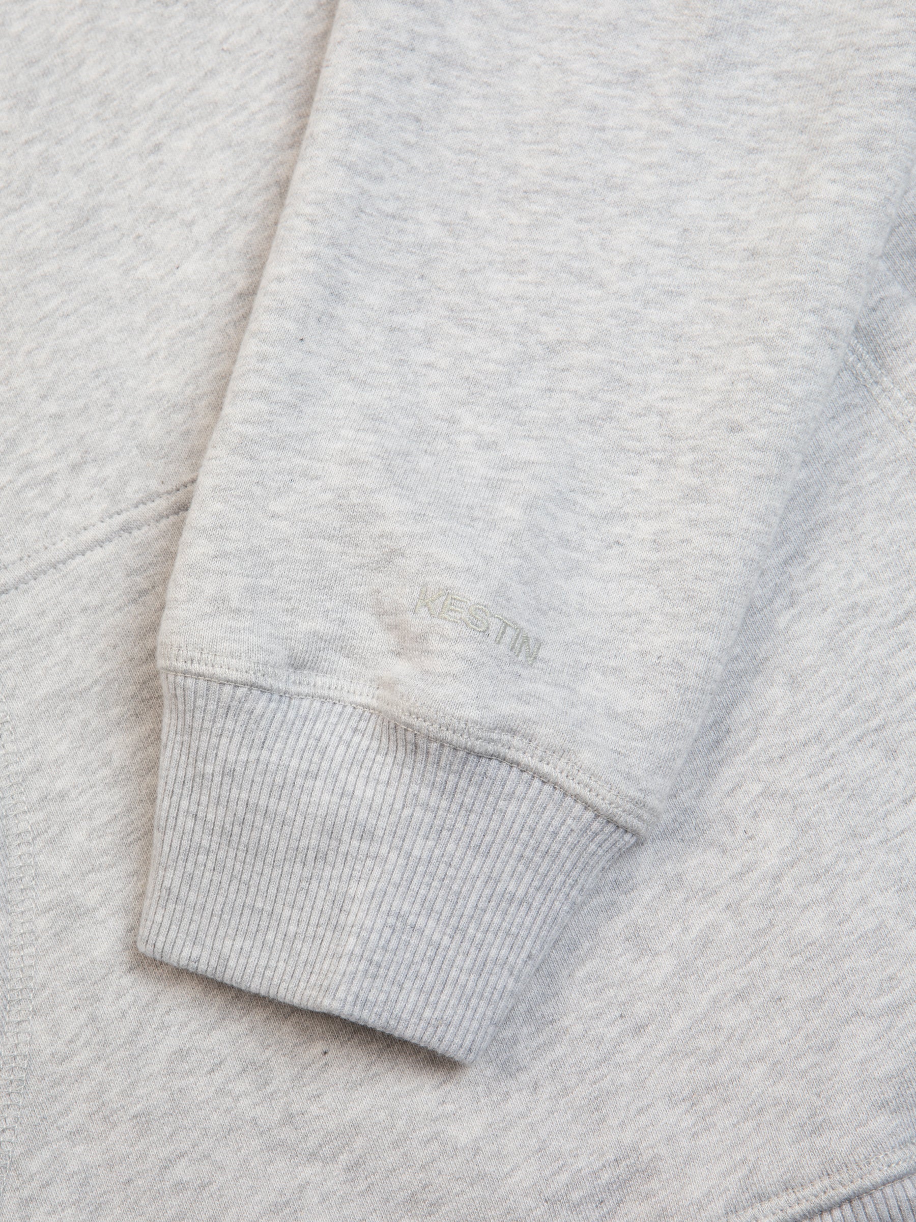 The ribbed cuff and subtle tonal logo of the St Andrews Hoodie in Grey Marl.