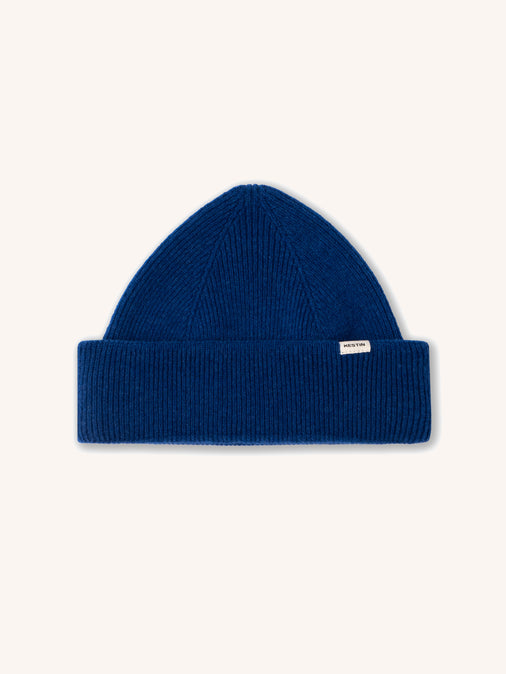 A cobalt blue beanie made from lambswool, on a white background.
