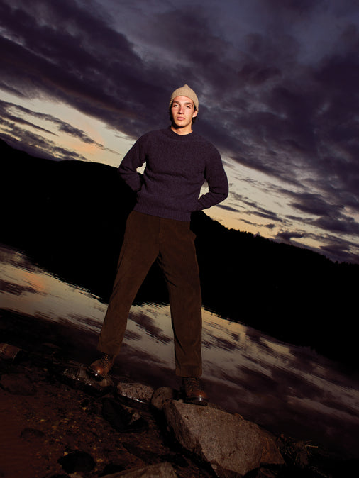 A man wearing a cable knit wool jumper by KESTIN, during dusk on the Isle of Skye.