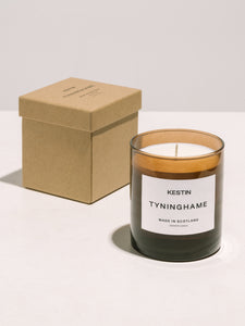 The Tyninghame Candle by KESTIN, sitting on a table next to its packaging box.