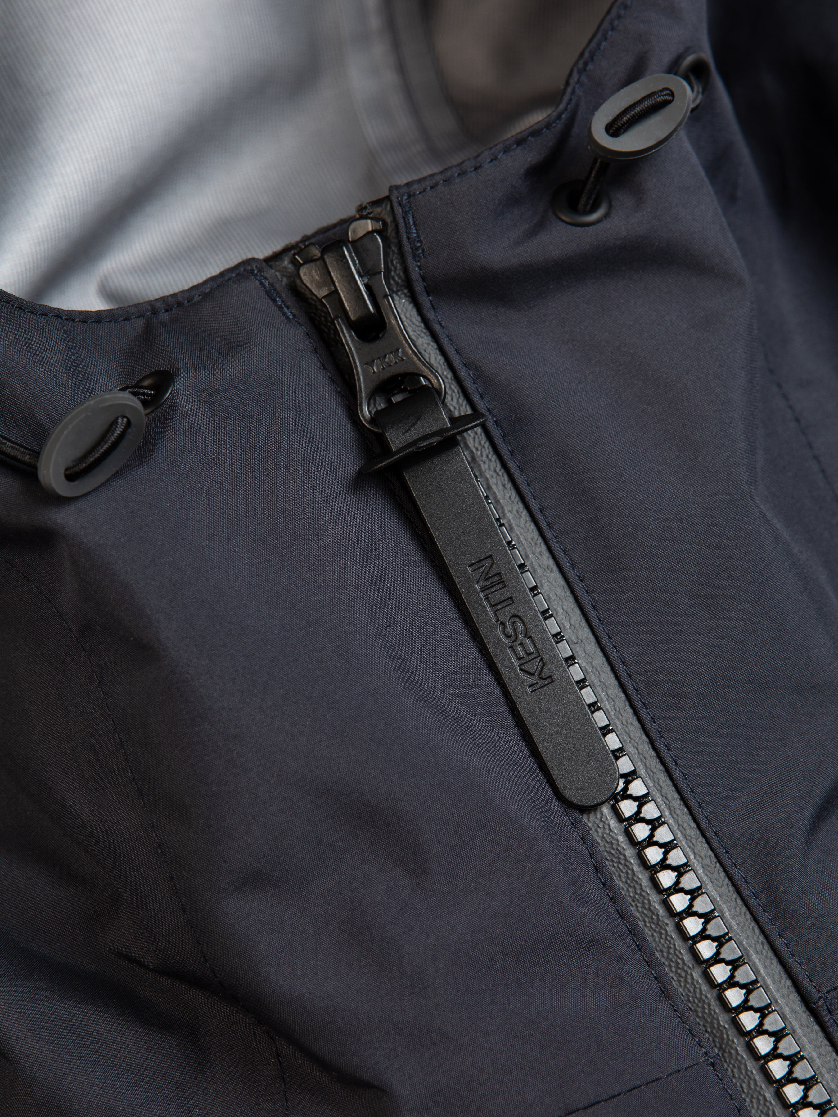 The zippered front and pull on a waterproof shell jacket in navy blue.