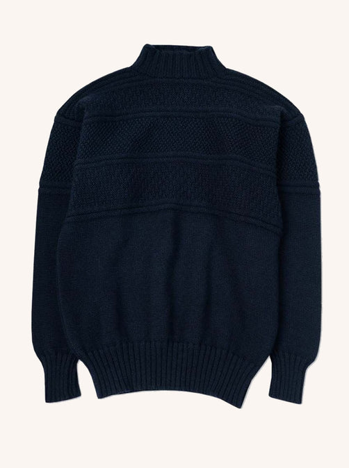 A navy blue knitted sweater made in Scotland from merino wool, on a white background.