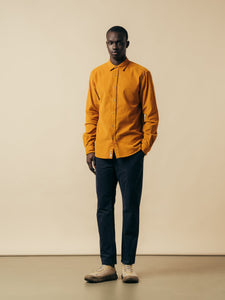 A man wearing a yellow shirt and navy trousers from Scottish designer KESTIN.