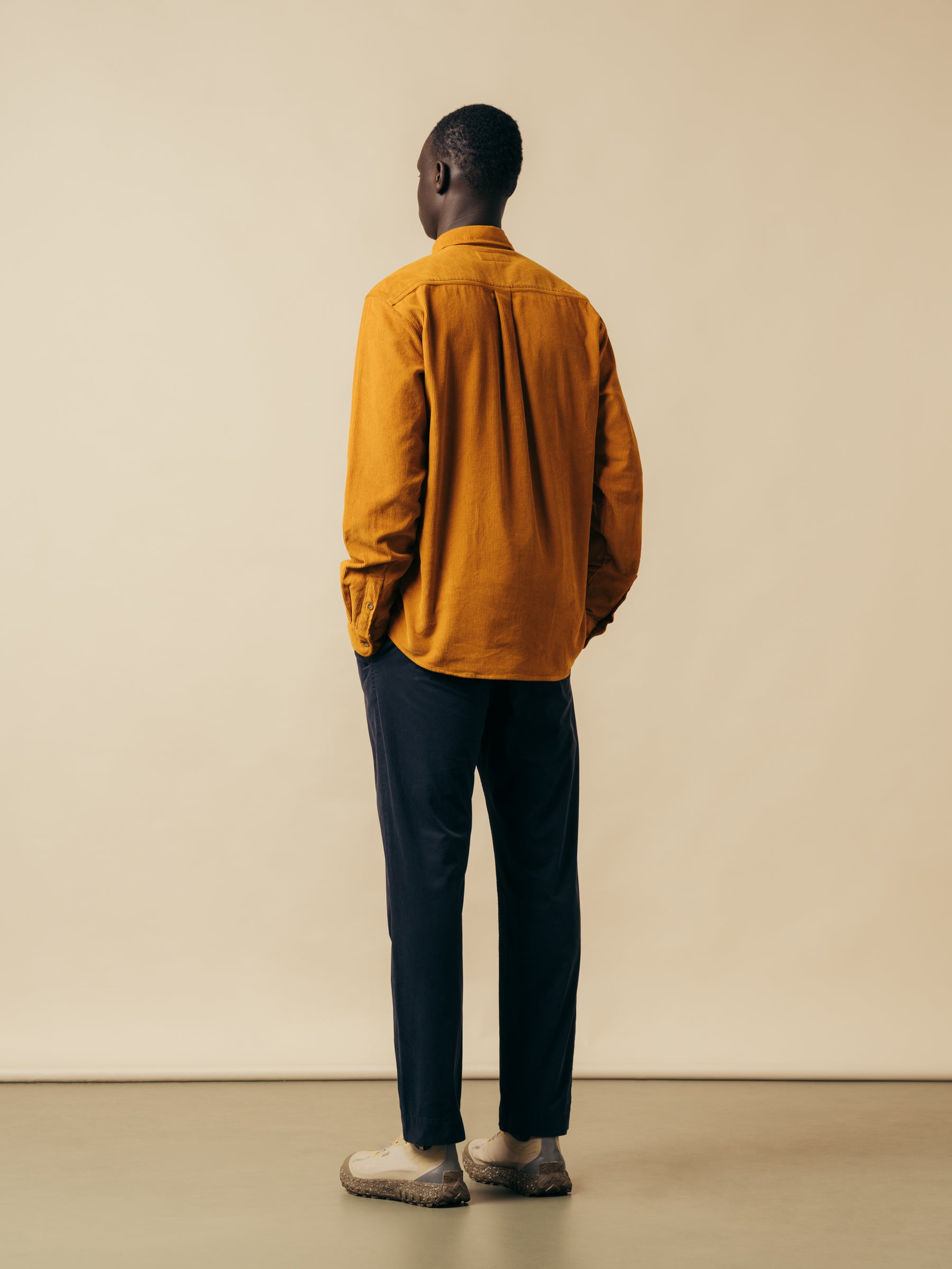A model wearing a yellow shirt and navy trousers from menswear brand KESTIN.