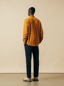 A model wearing a yellow shirt and navy trousers from menswear brand KESTIN.