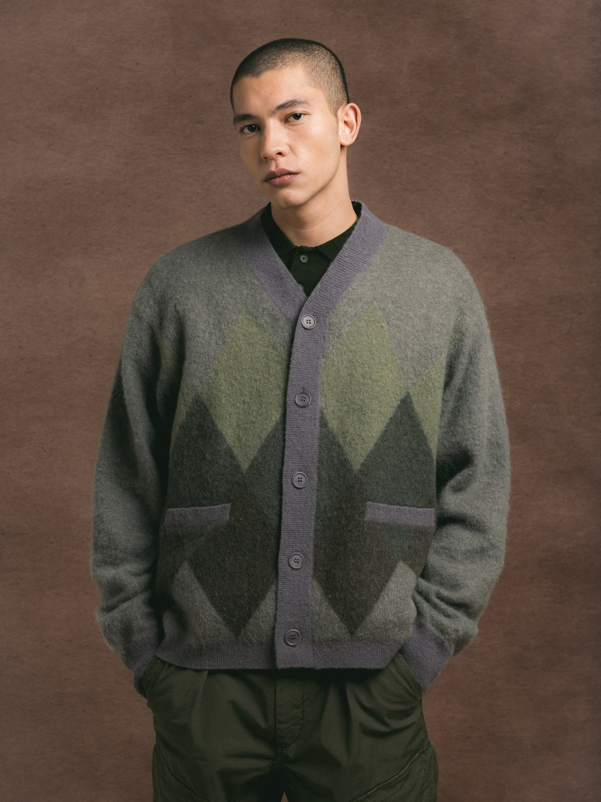 Man wearing a patterned cardigan against a brown background