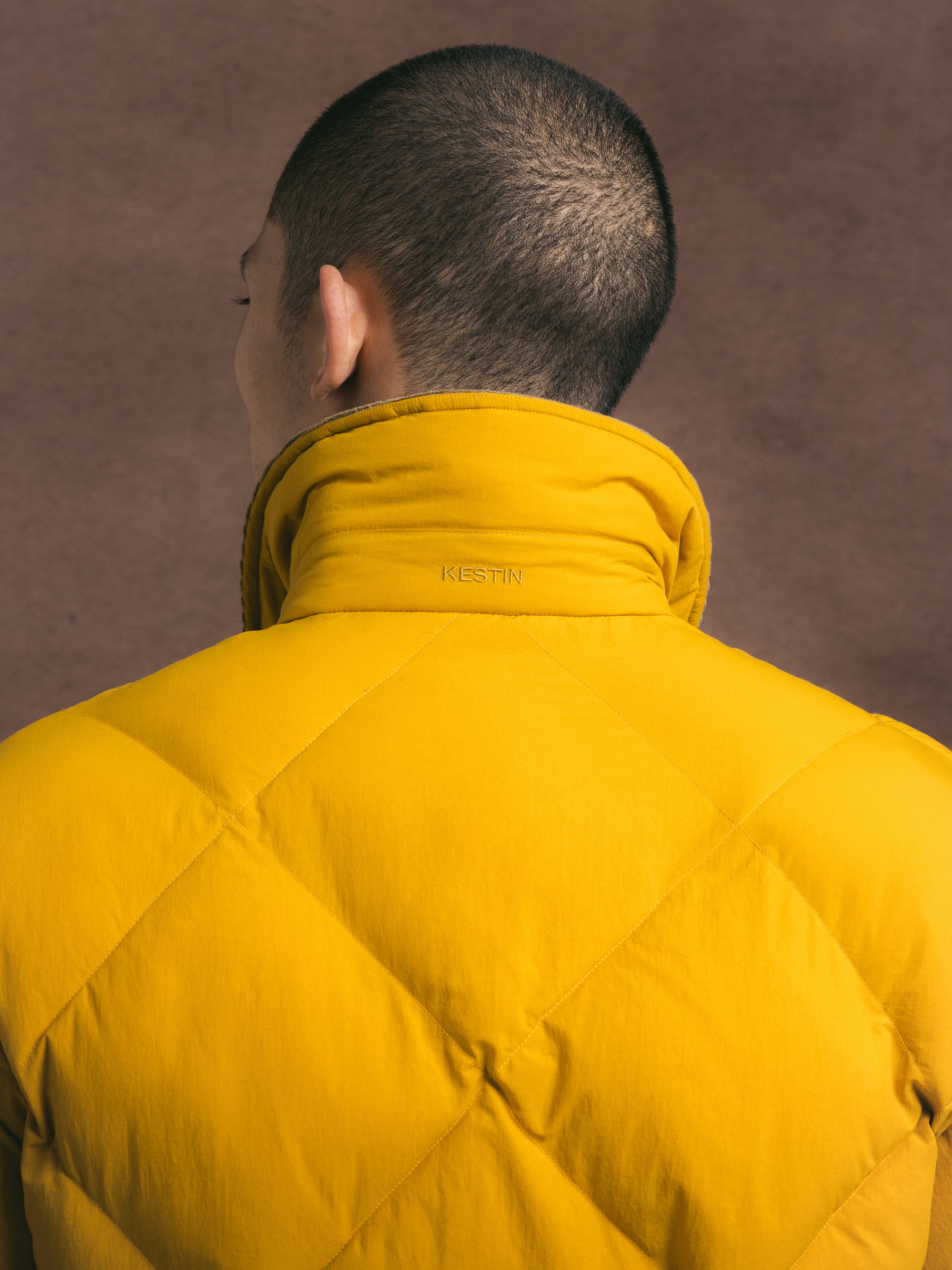 Men wearing a yellow puffer jacket with a blurred background