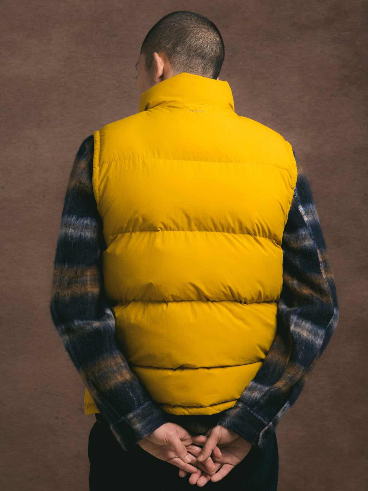 Person wearing a yellow puffer vest over a wool jacket