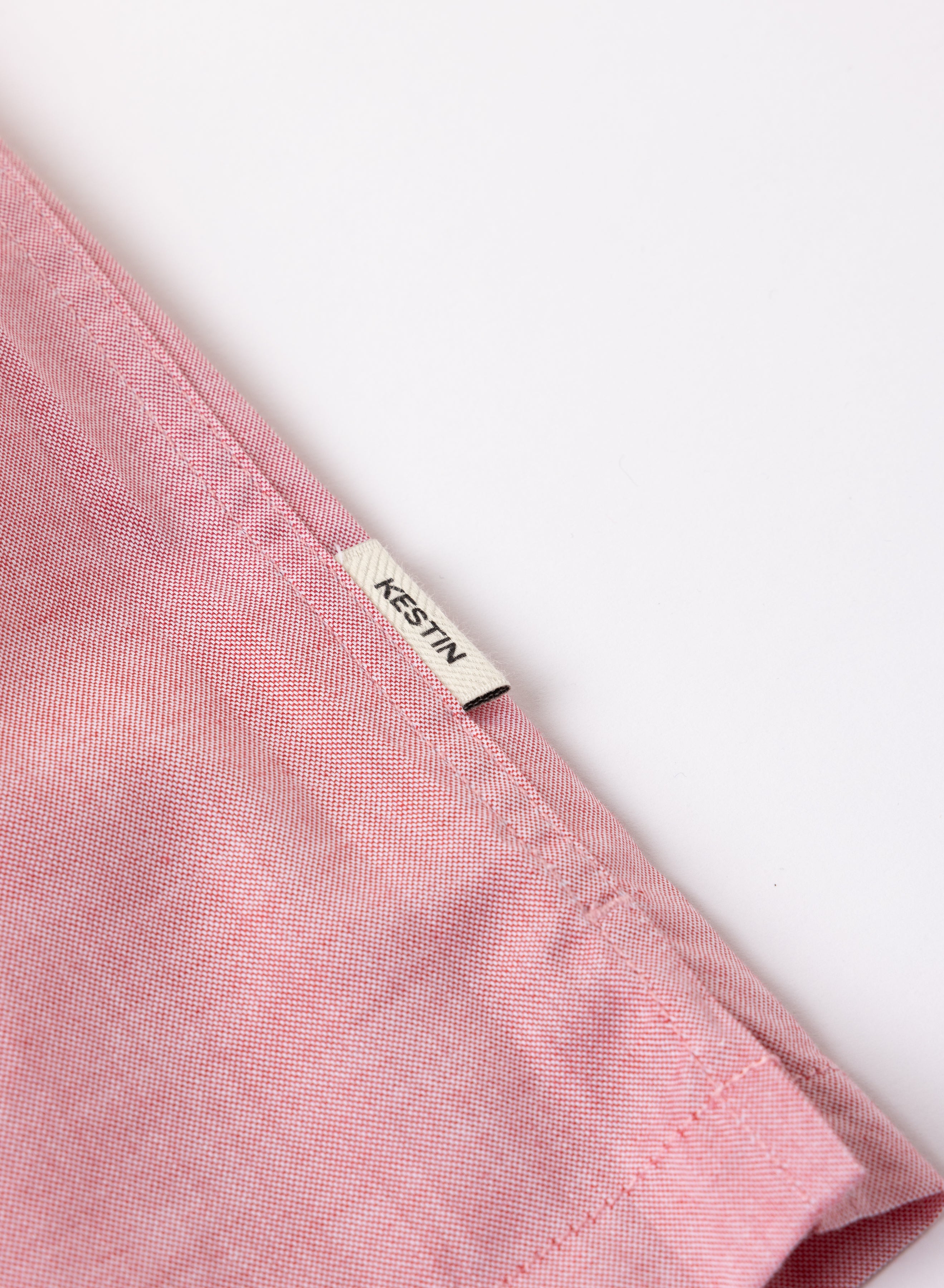 Close-up of a pink fabric with a Kestin label on a white background