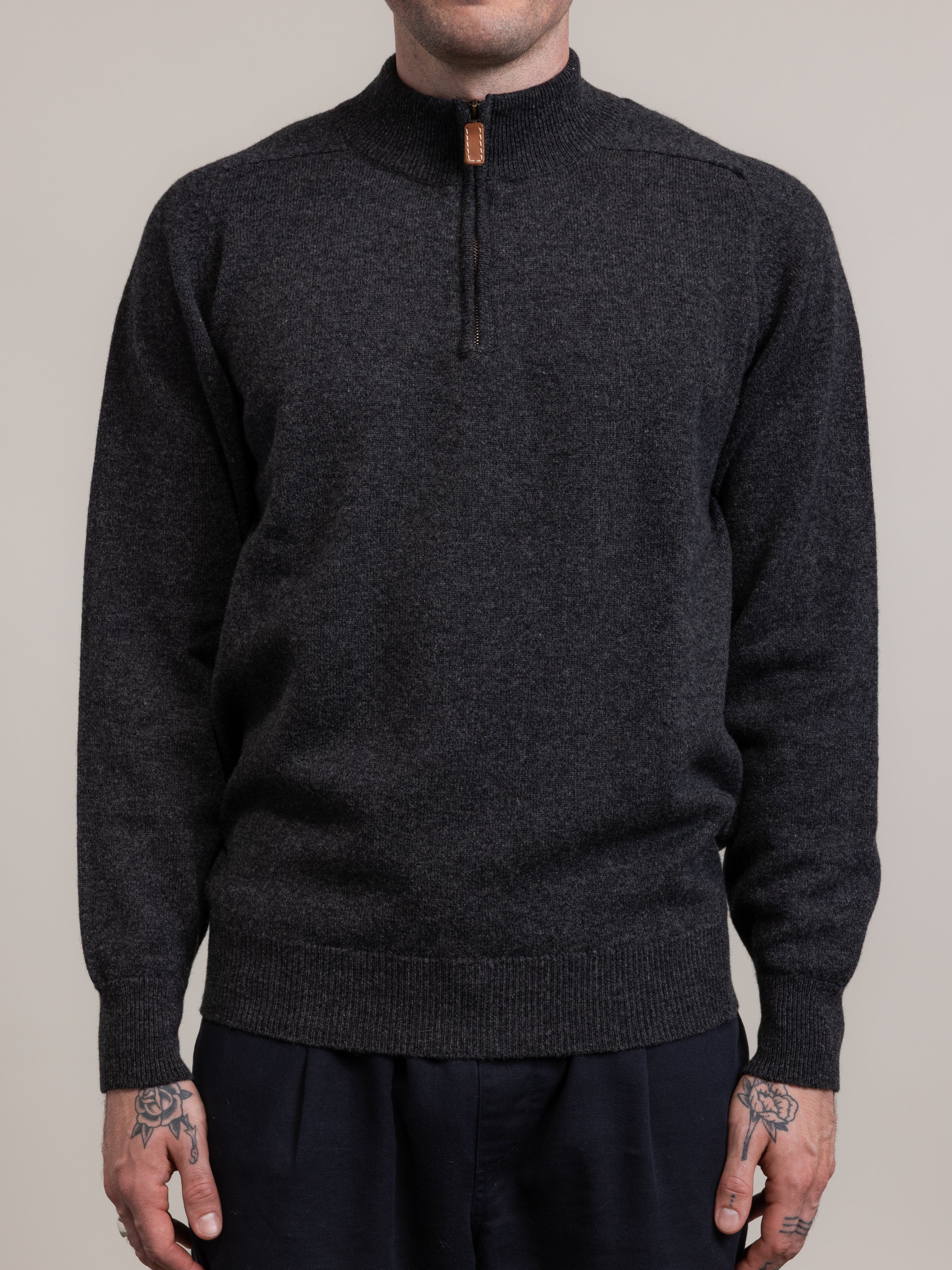 Dark gray sweater worn by a person on a plain background