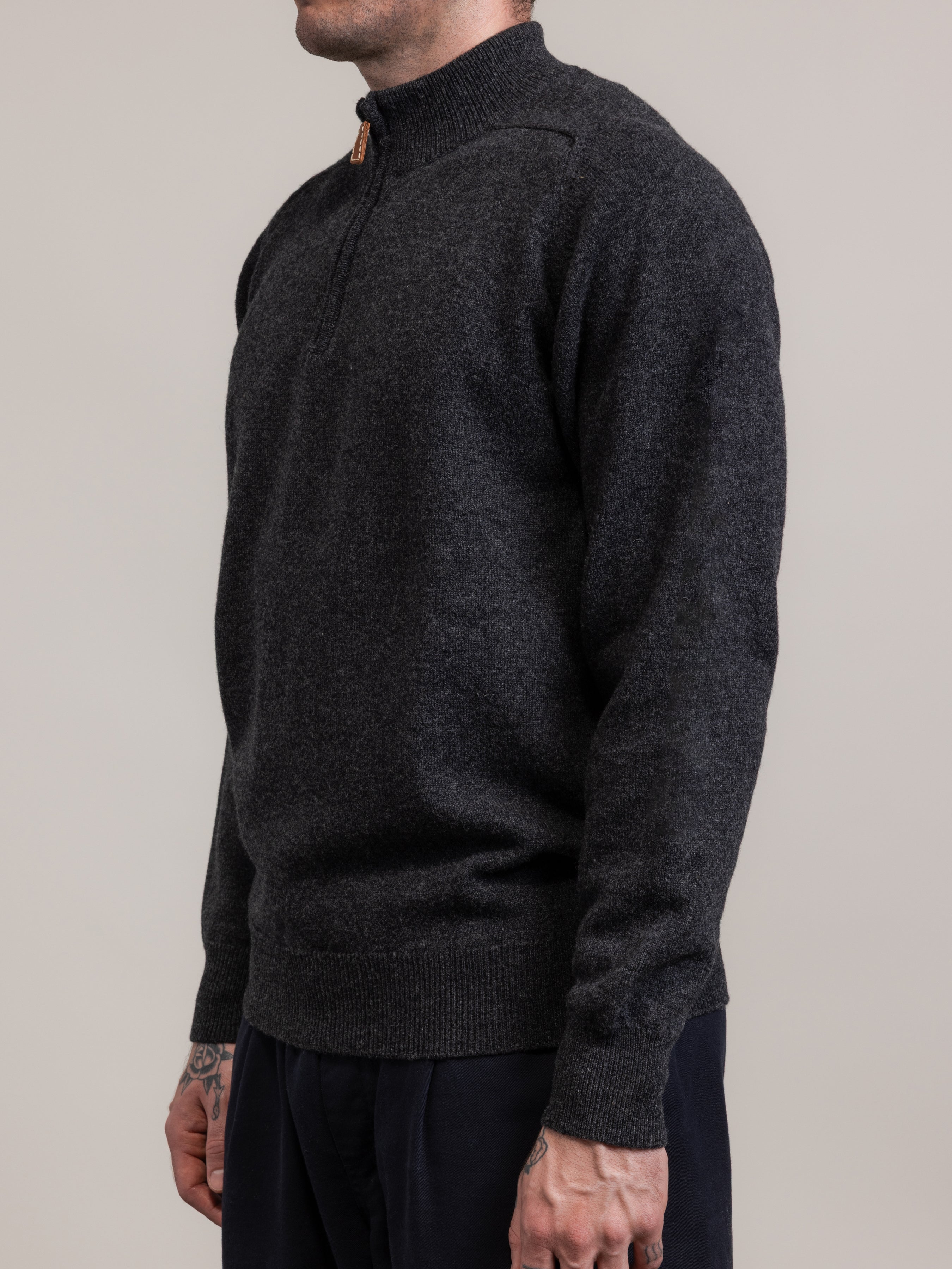 Person wearing a dark gray sweater against a plain background