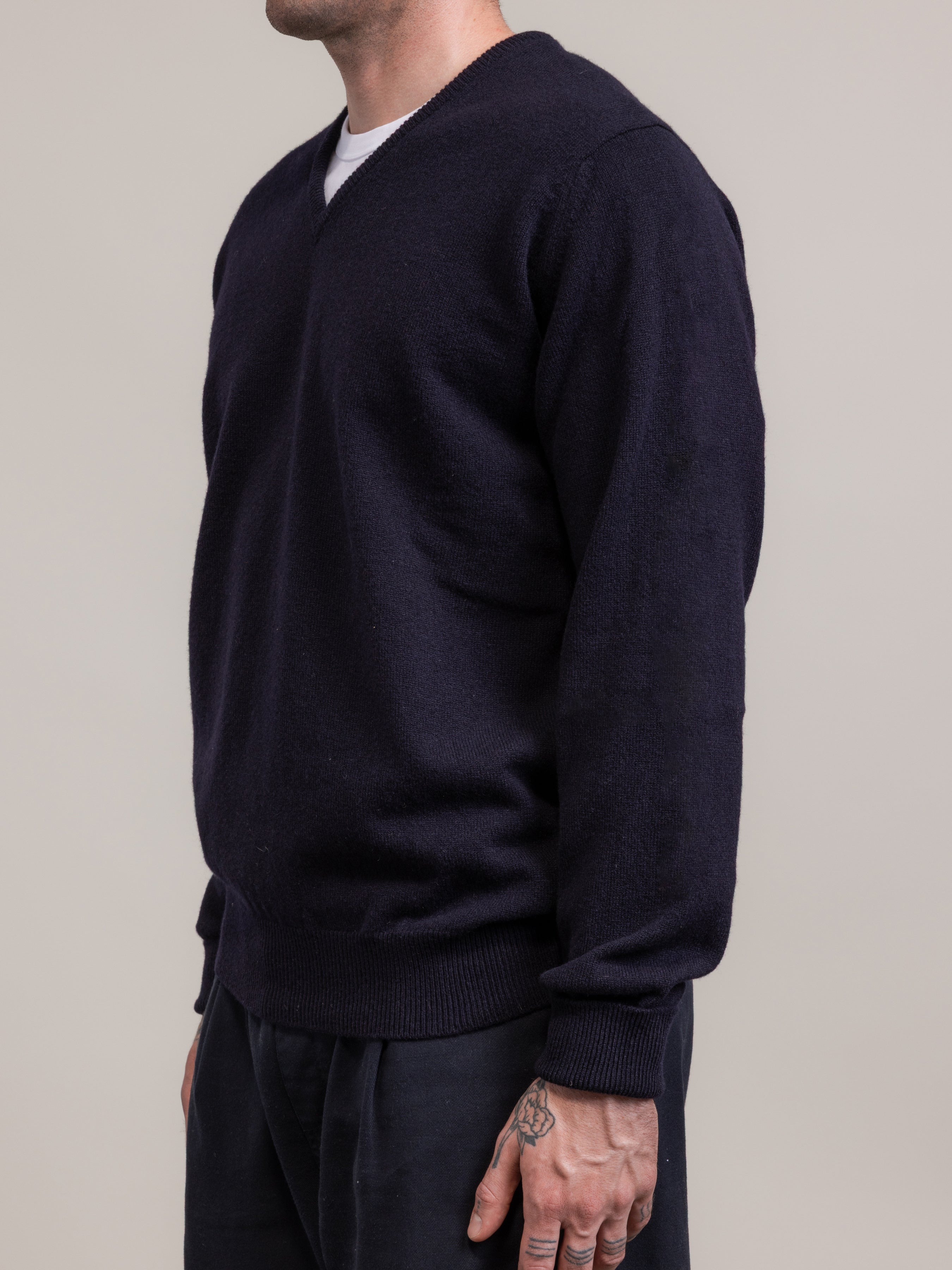 Person wearing a dark blue sweater against a plain background