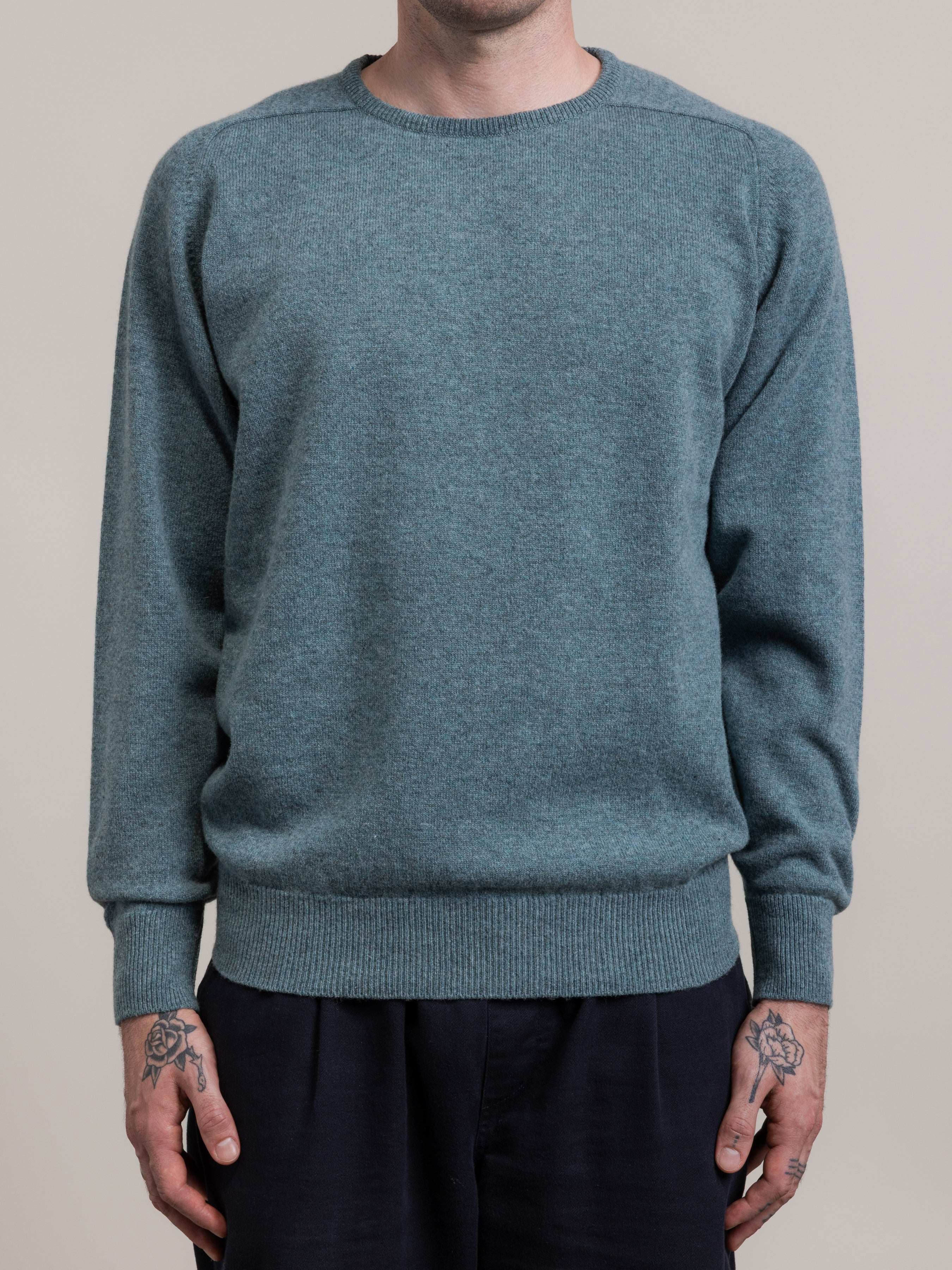 Person wearing a teal sweater against a plain background