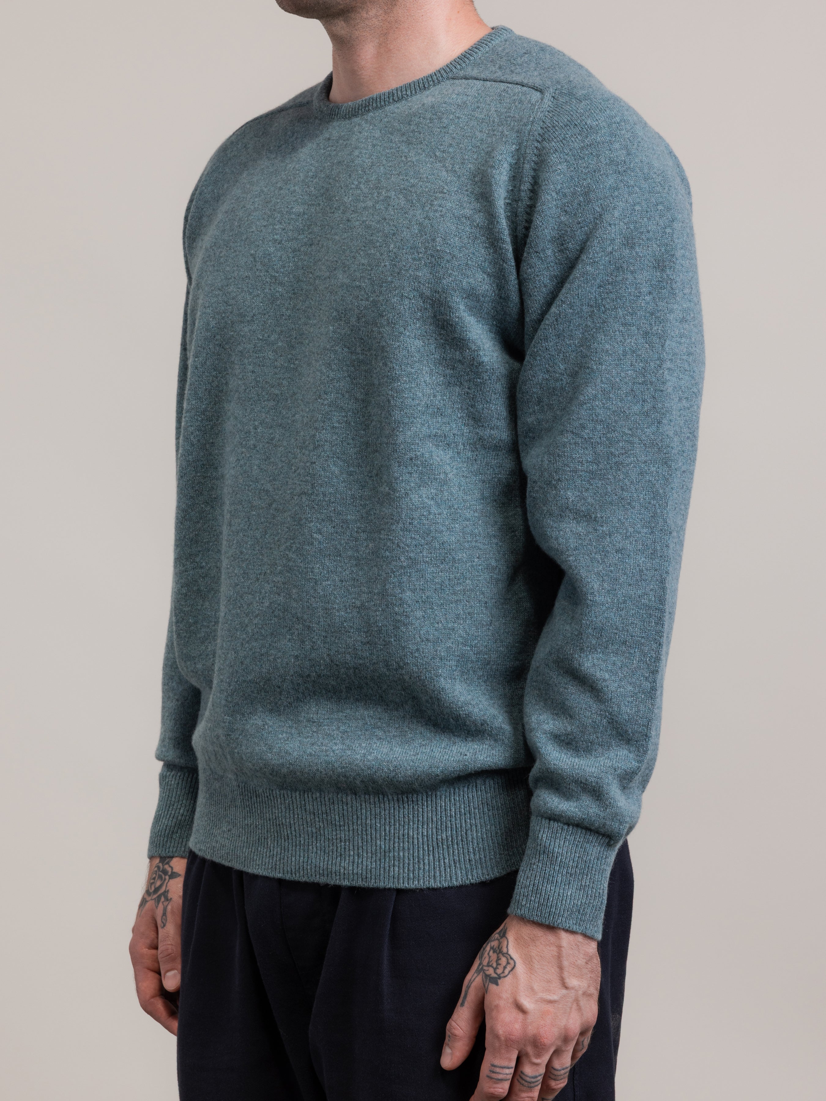 Person wearing a teal sweater against a plain background